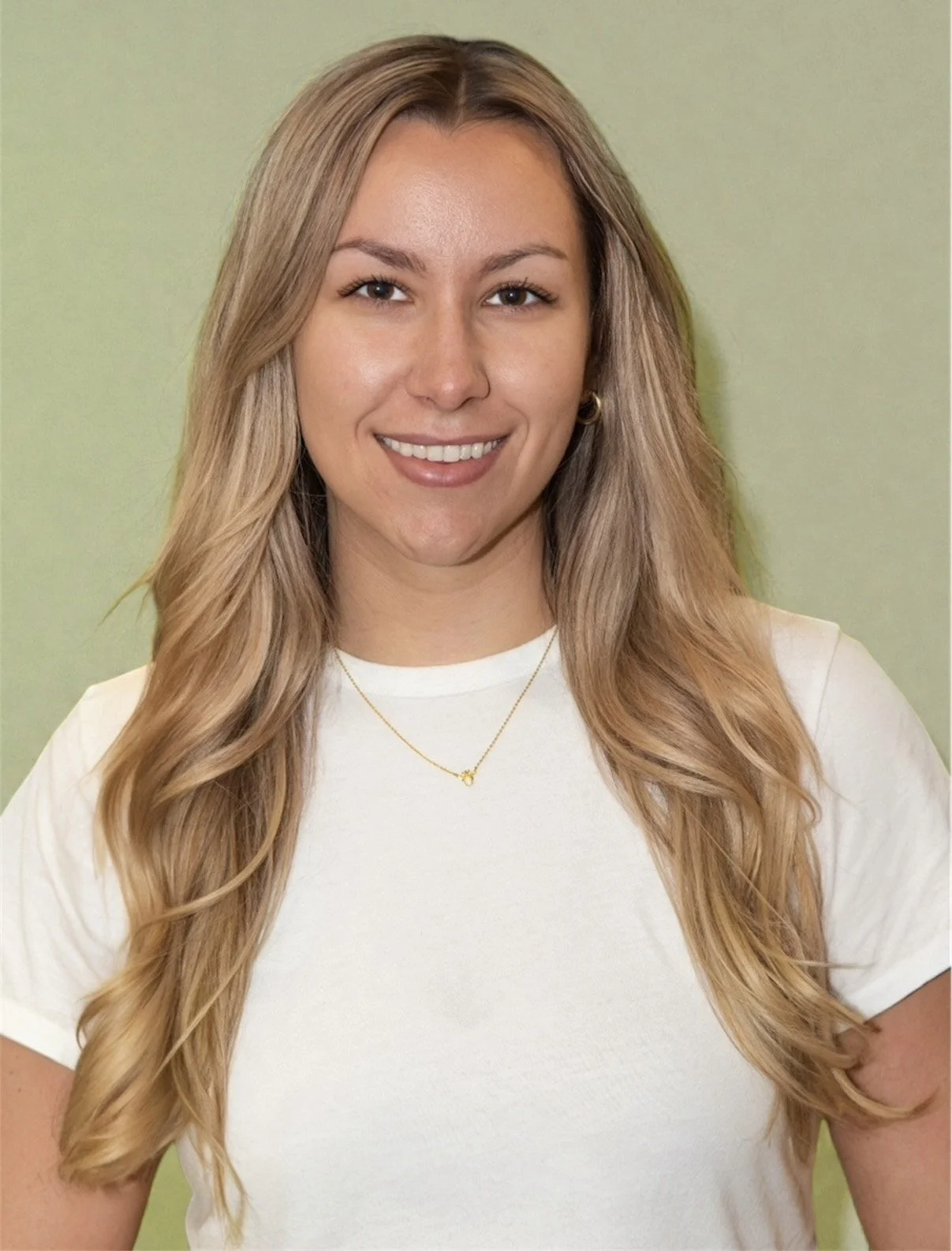 Melissa, RD with WebRD, with long, wavy hair smiling outdoors, wearing a green sweater.