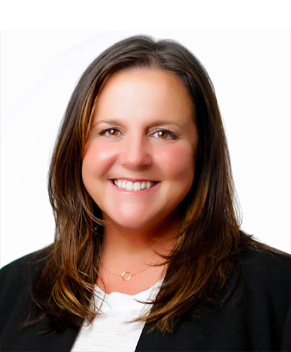 Headshot of a woman with brown hair smiling, wearing a black blazer and white top, against a plain white background.
