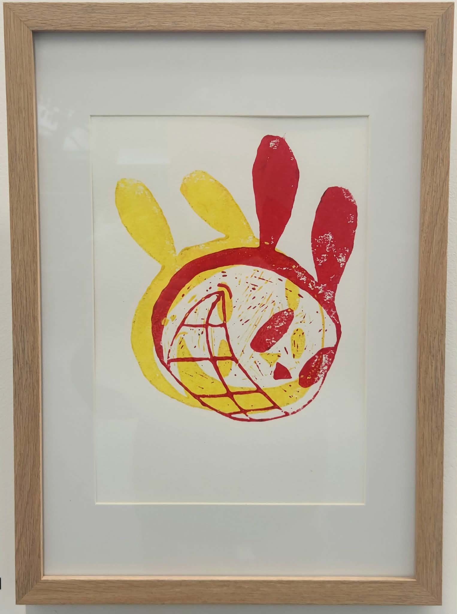 Framed yellow and red bunny head moving down lino print