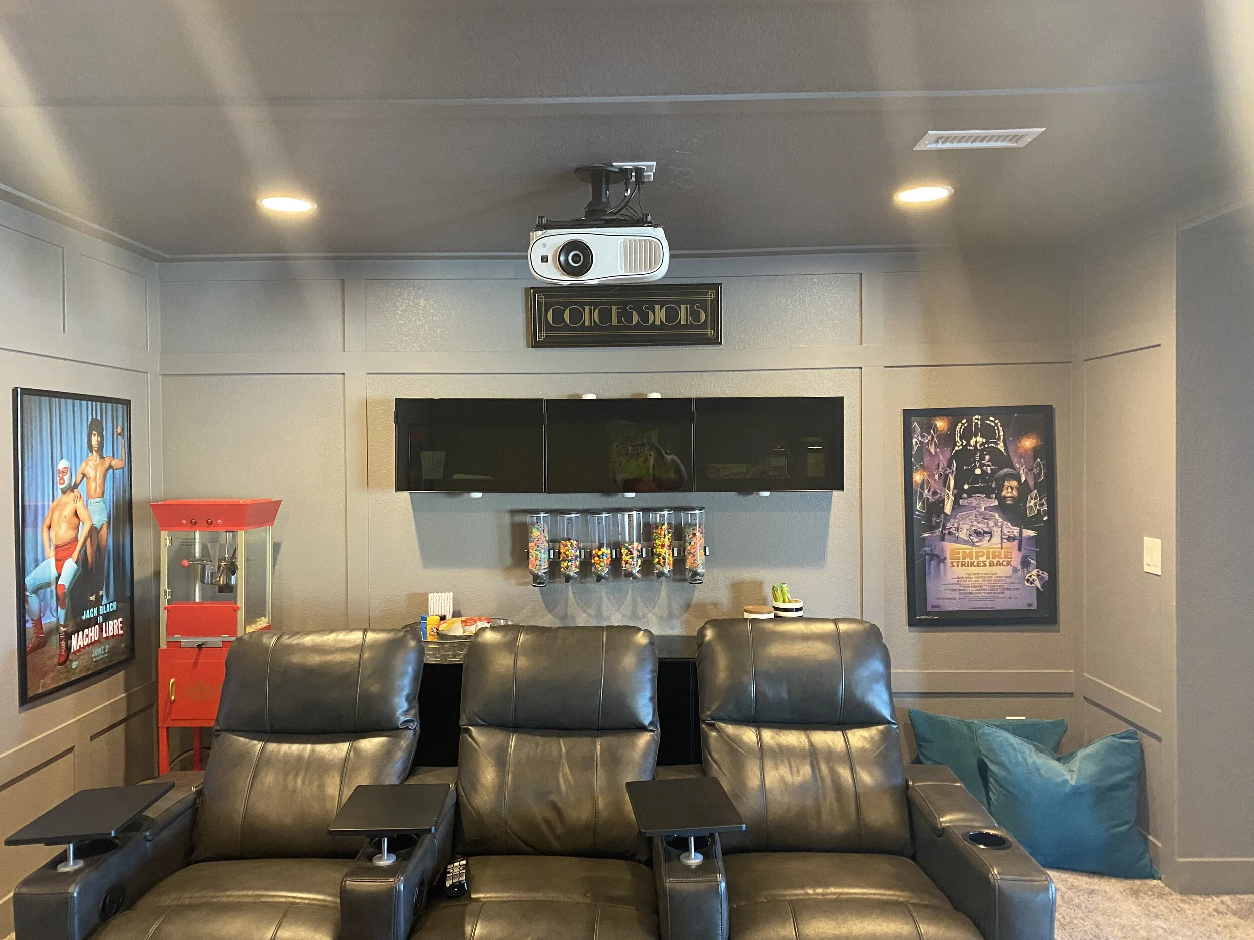 This theater room is comfortable and equipped with everything needed for Family Movie Night! Recliners, dimmers on the lights, floor lighting, movie posters, and a fully equipped concessions center with a popcorn machine. Custom room darkening curt