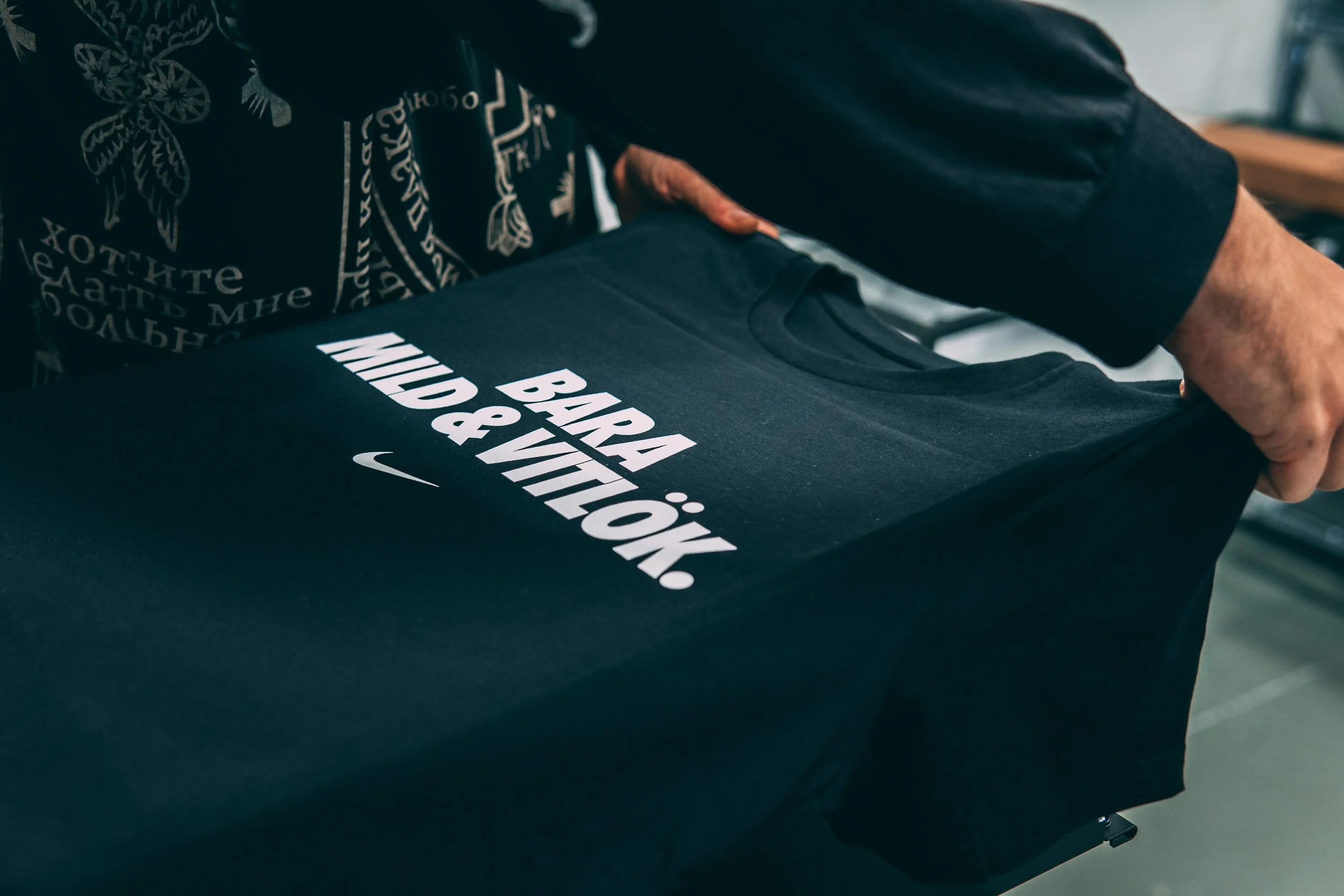 En person håller i en svart t-shirt med vit text som säger 'BARA BÅDE MILJÖ & VÅR PLANET'