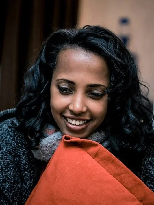 Woman smiling holding orange cushion