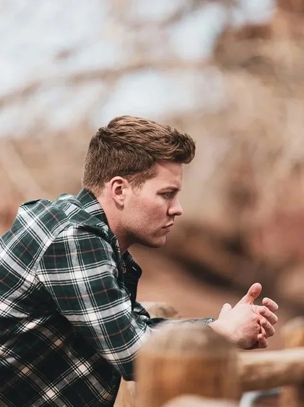 Mean wearing neck shirt leaning on barrier