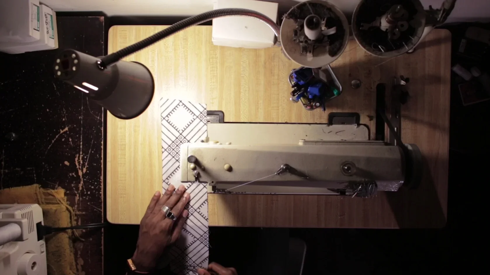 Hands feeding patterned fabric through a vintage stitching machine — still from a THEY production for Etsy.