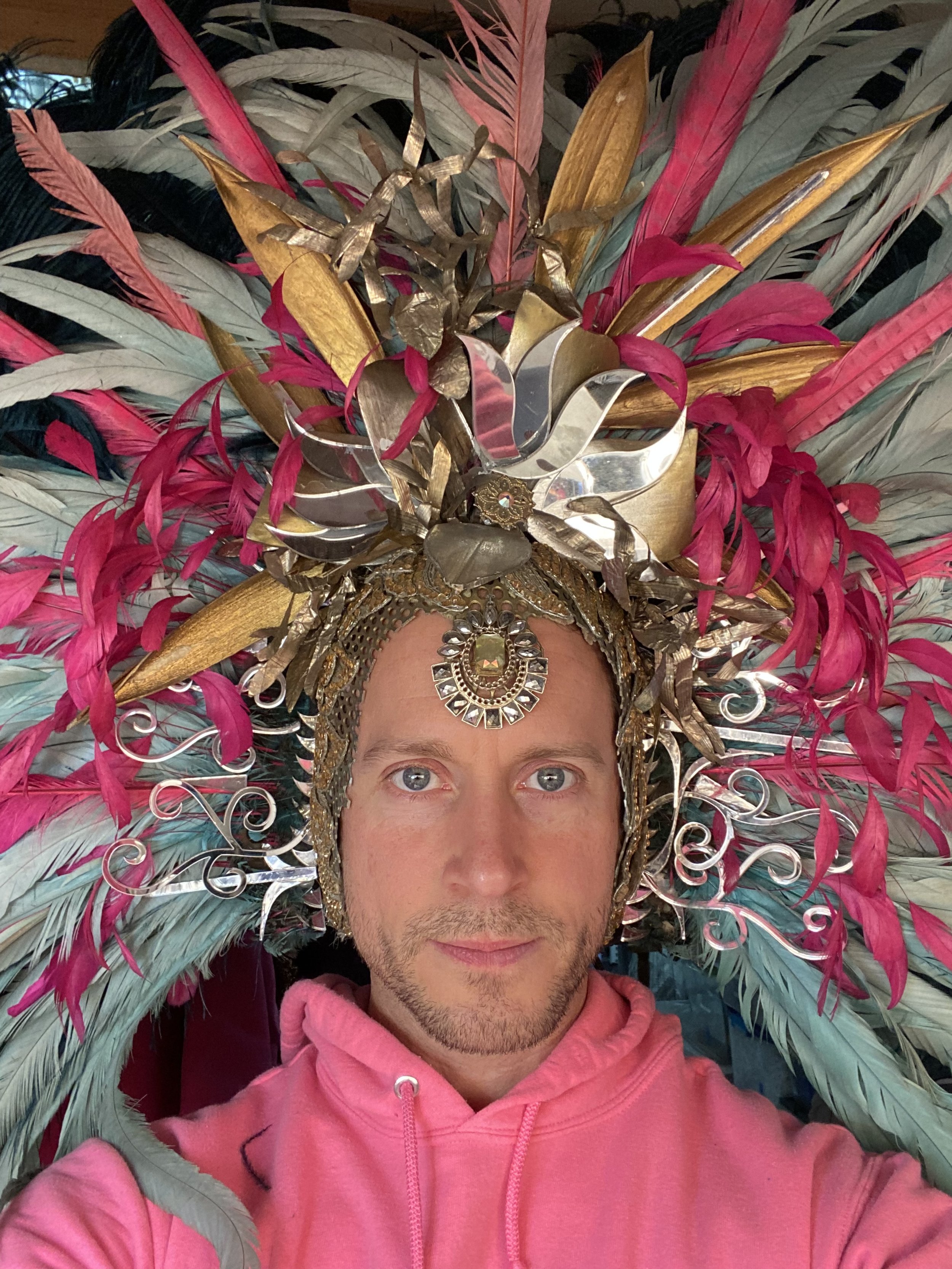 Darrell in elaborate custom headress with colorful feathers and gold flourishes.jpeg