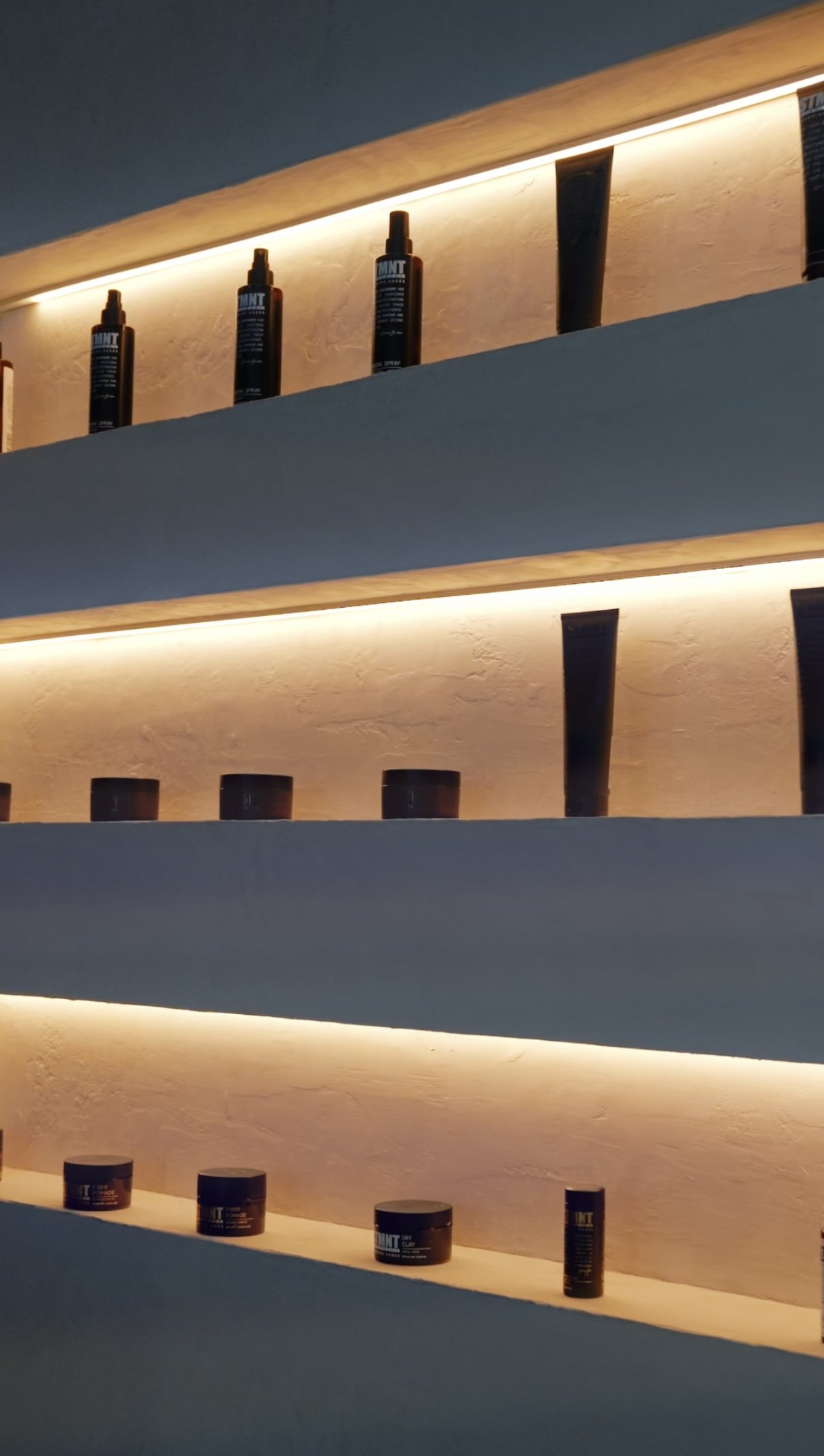 Shelves with black spray bottles and containers, backlit with warm lighting in a modern display