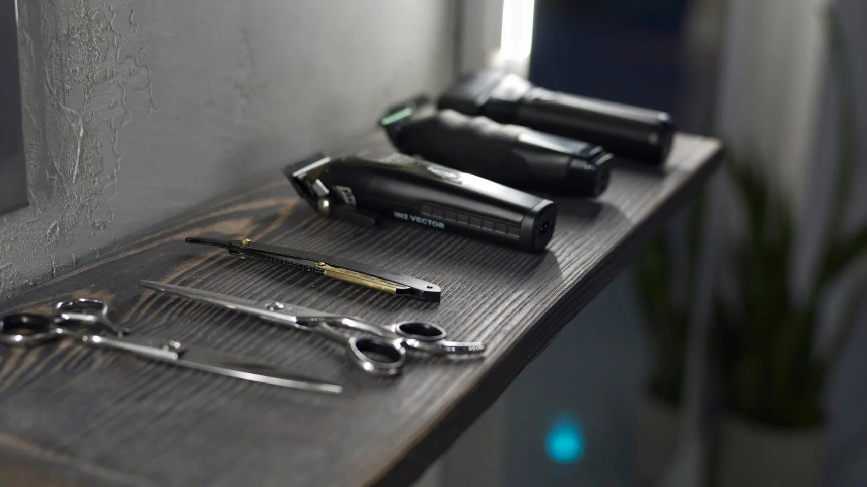 A wooden barber station with hair clippers, scissors, and straight razors laid out.