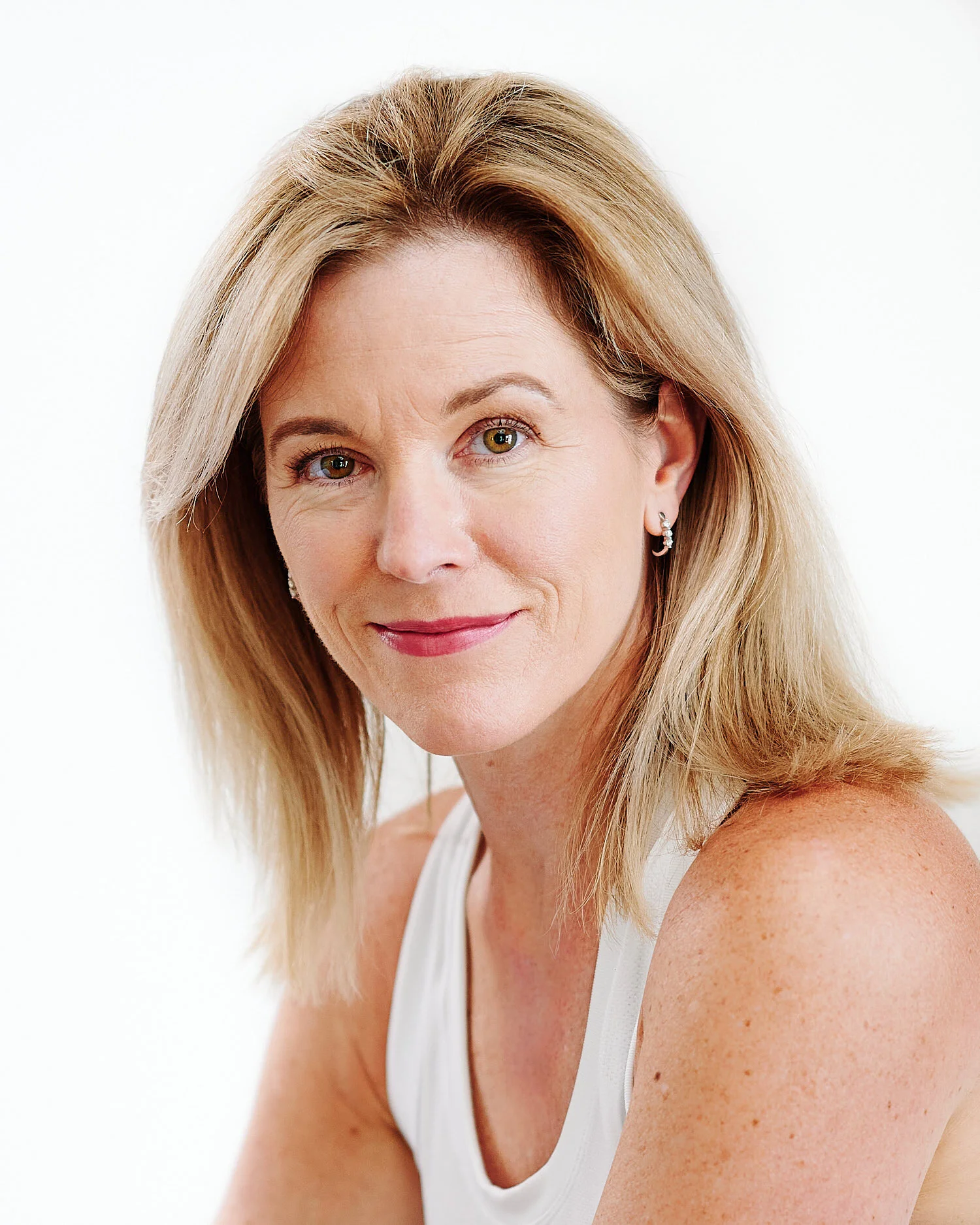  A beautiful woman in her fifties posing for a headshot in a photography studio with white background. Julie Trovato is smiling, her eyes are sparkling. She looks confident, friendly and open. 