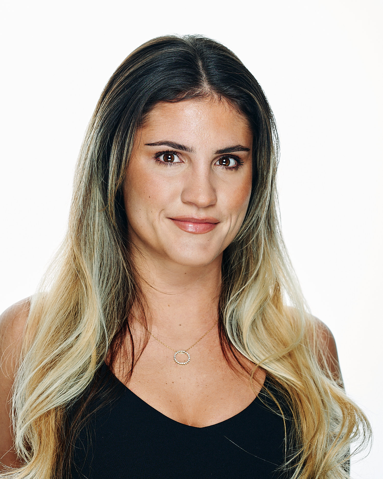  Stephanie Gibbs is posing for a professional business headshot in a photography studio against white background. The young woman has a beautiful face with olive skin, large brown eyes with long lashes 