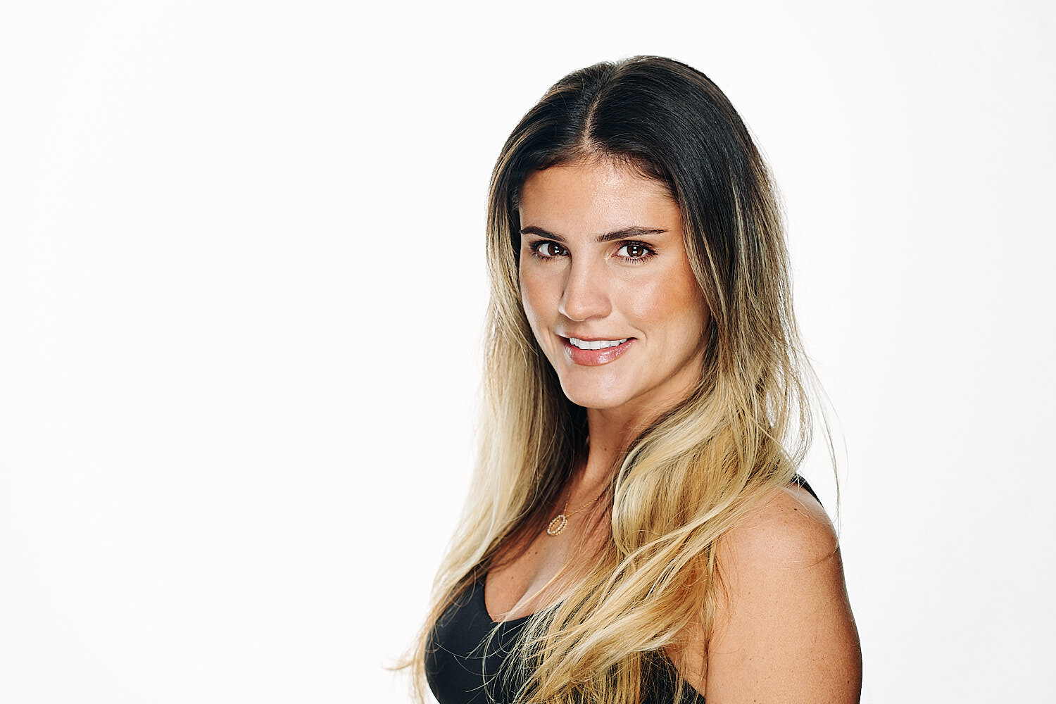  Stephanie Gibbs is posing for a professional business headshot in a photography studio against white background. The young woman has a beautiful face with olive skin, large brown eyes with long lashes 