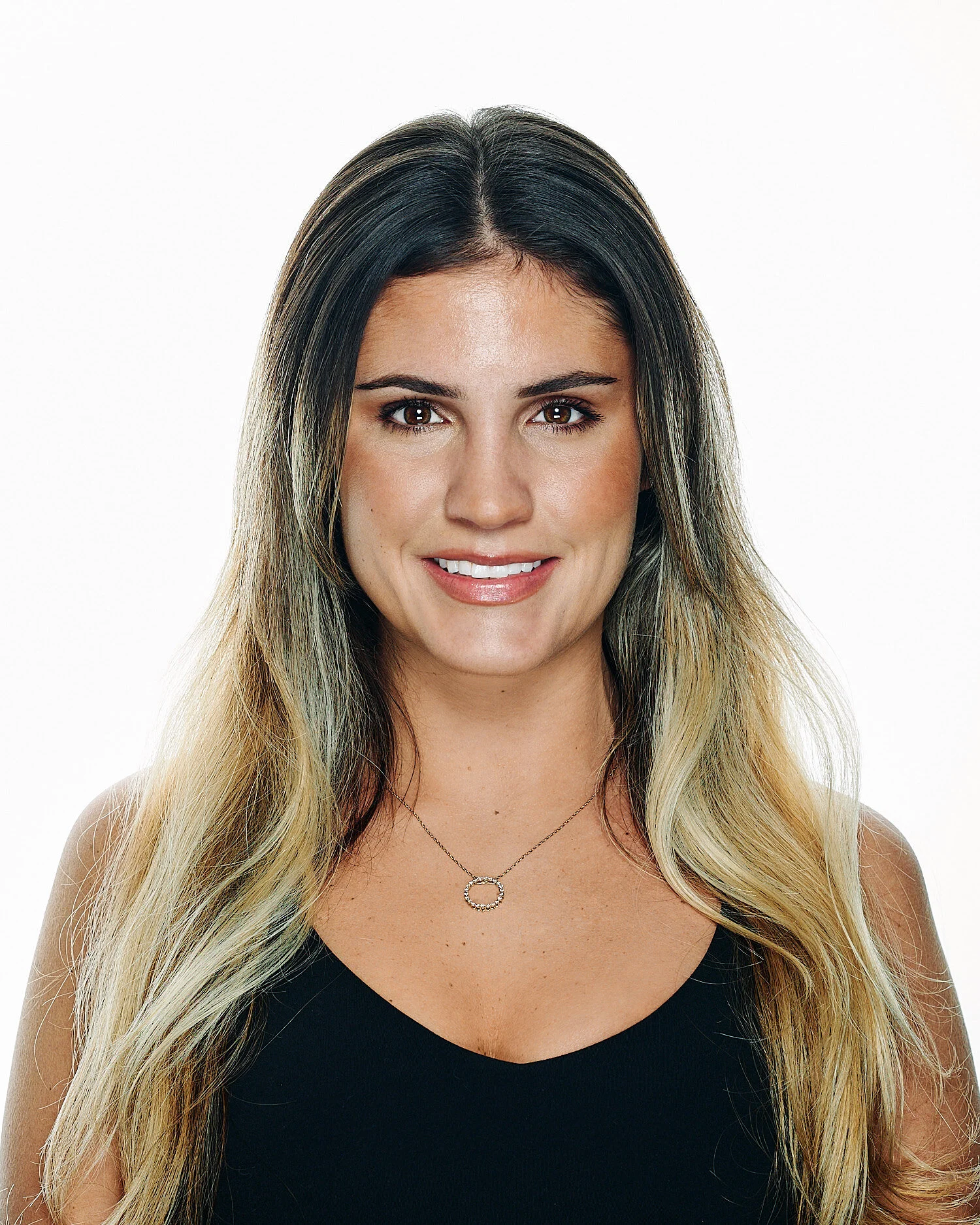  Stephanie Gibbs is posing for a professional business headshot in a photography studio against white background. The young woman has a beautiful face with olive skin, large brown eyes with long lashes 