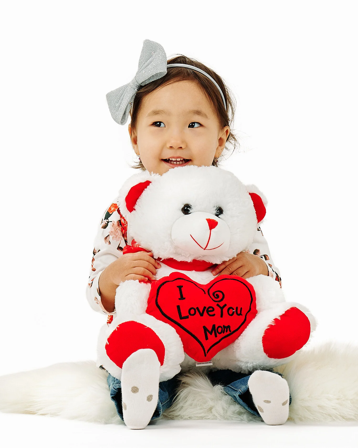  Gulmira Azamatova is posing for her 2nd birthday photos with her mother Nuriza Dobutova and her father Azamat Anapiiaev and her favorite toys. They are in a pro photo studio with white background. 
