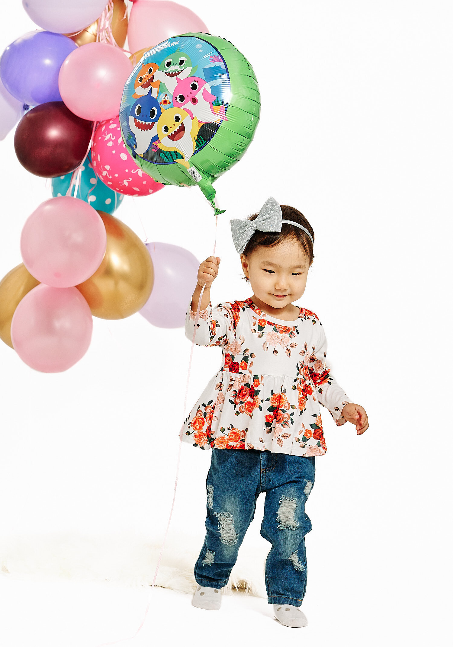  Gulmira Azamatova is posing for her 2nd birthday photos with her mother Nuriza Dobutova and her father Azamat Anapiiaev and her favorite toys. They are in a pro photo studio with white background. 