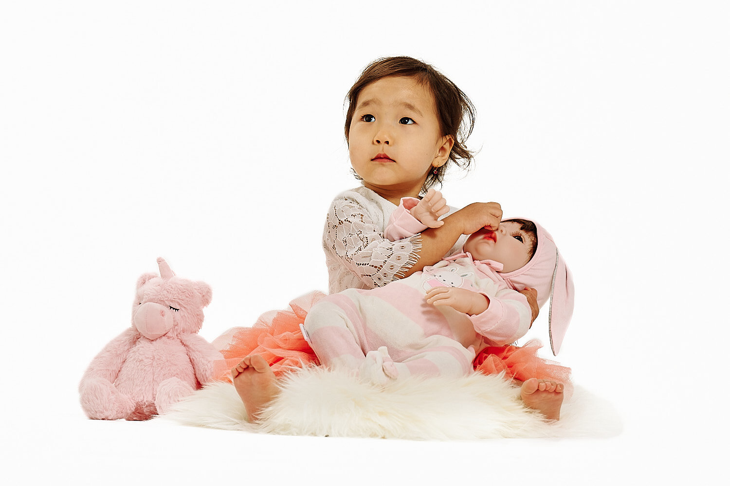  Gulmira Azamatova is posing for her 2nd birthday photos with her mother Nuriza Dobutova and her father Azamat Anapiiaev and her favorite toys. They are in a pro photo studio with white background. 