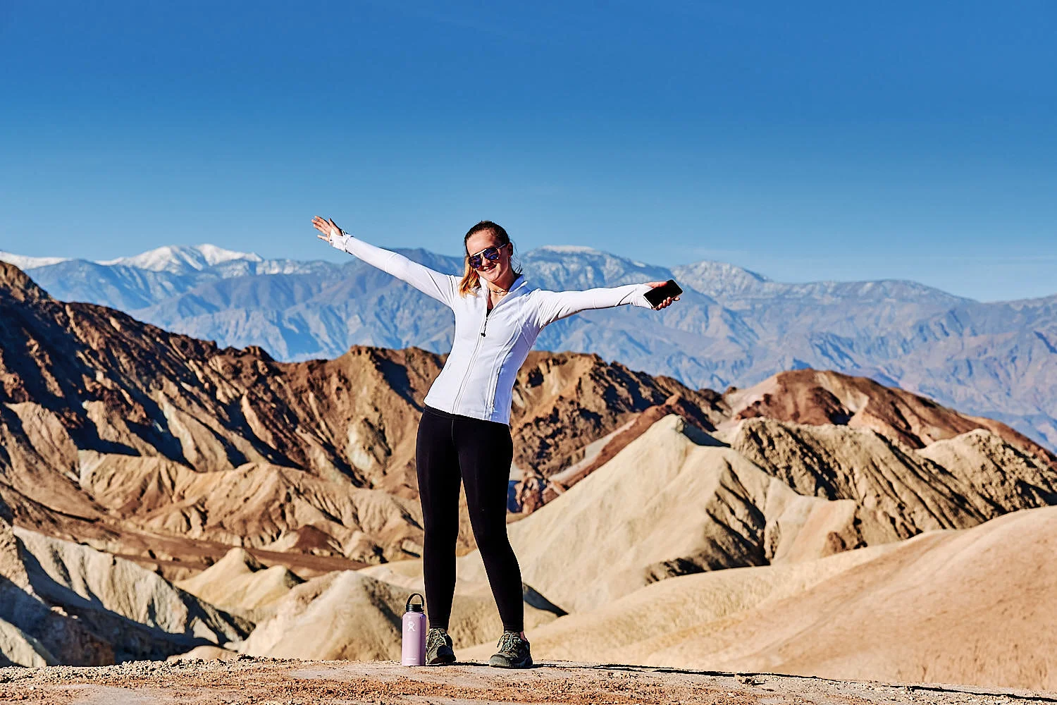  A family hike from Zabriskie Point in Death Valley national park in california. Huge sand dunes, terracotta mountains and hazy horizons are shining against clear blue sky in the midday sun. 