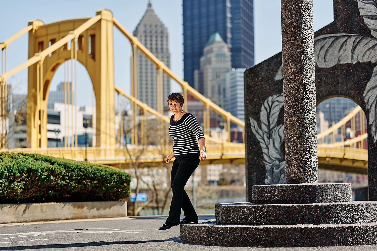  Pittsburgh downtown at midday in early April 2021 with yellow bridges in the background and cherry blossom in the foreground. A couple is photographing each other for happy environmental portraits. 