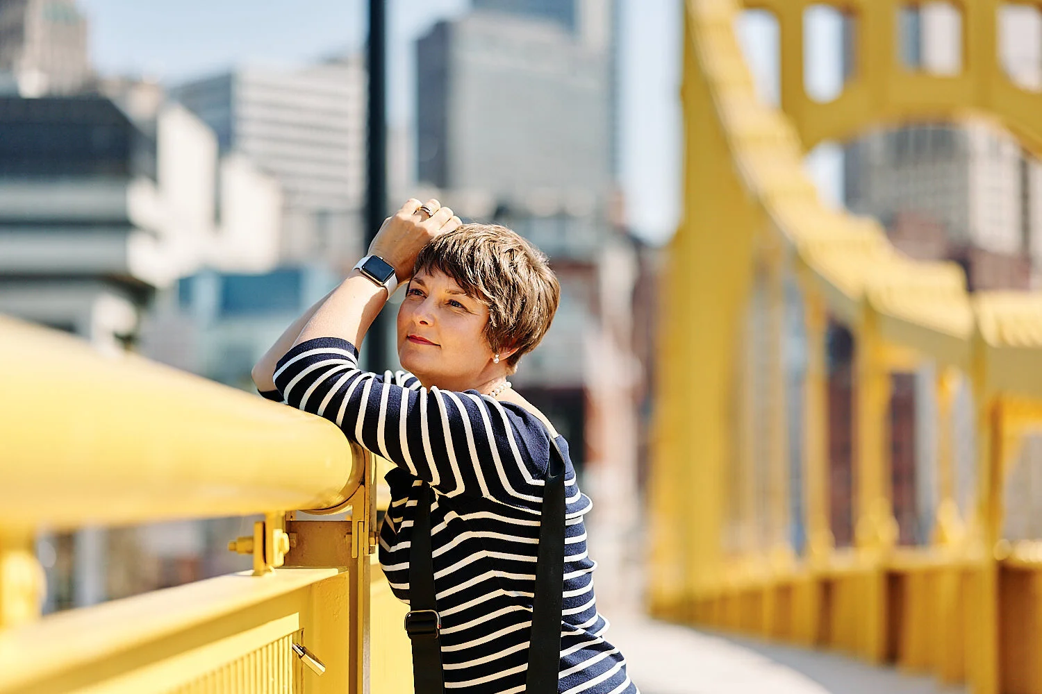  Pittsburgh downtown at midday in early April 2021 with yellow bridges in the background and cherry blossom in the foreground. A couple is photographing each other for happy environmental portraits. 