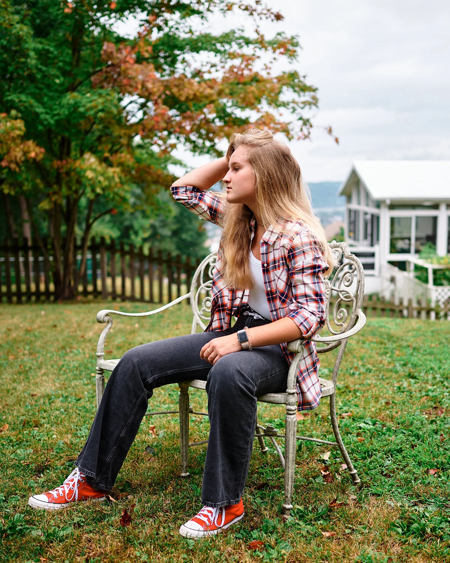  Alena is posing for a moody teenager photo series in her backyard on a rainy evening in Pittsburgh, Pennsylvania. She is dressed in her new checked shirt and flare jeans and looks cool and stylish. 