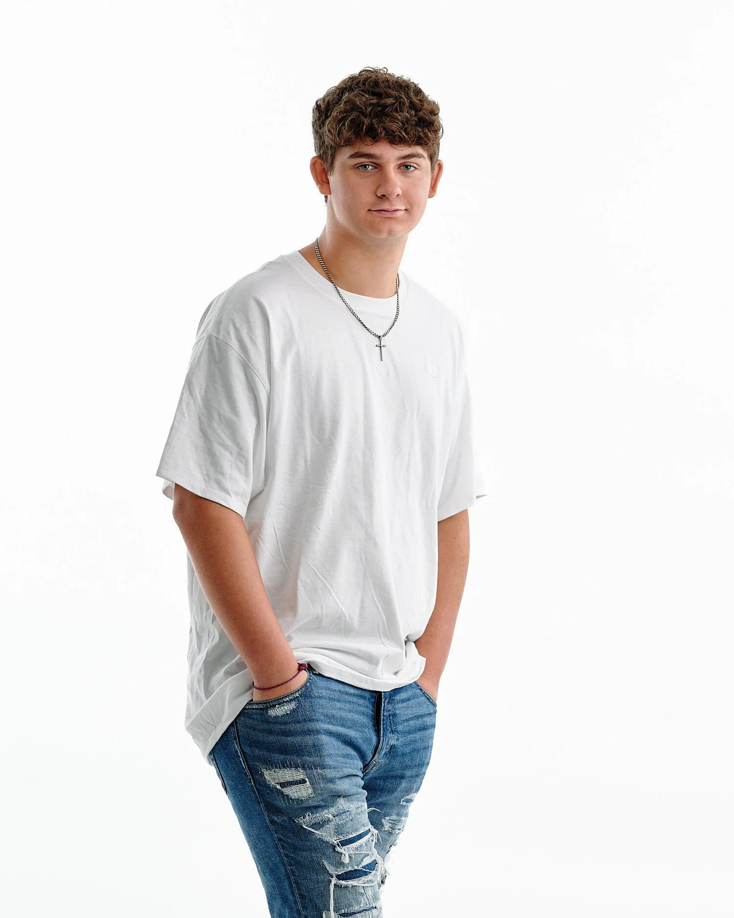  William Mickle is posing for high school senior portraits. He looks handsome in his black suit and aquamarine shirt and blue jeans and white t-shirt. He has large grey eyes and curly hair. 