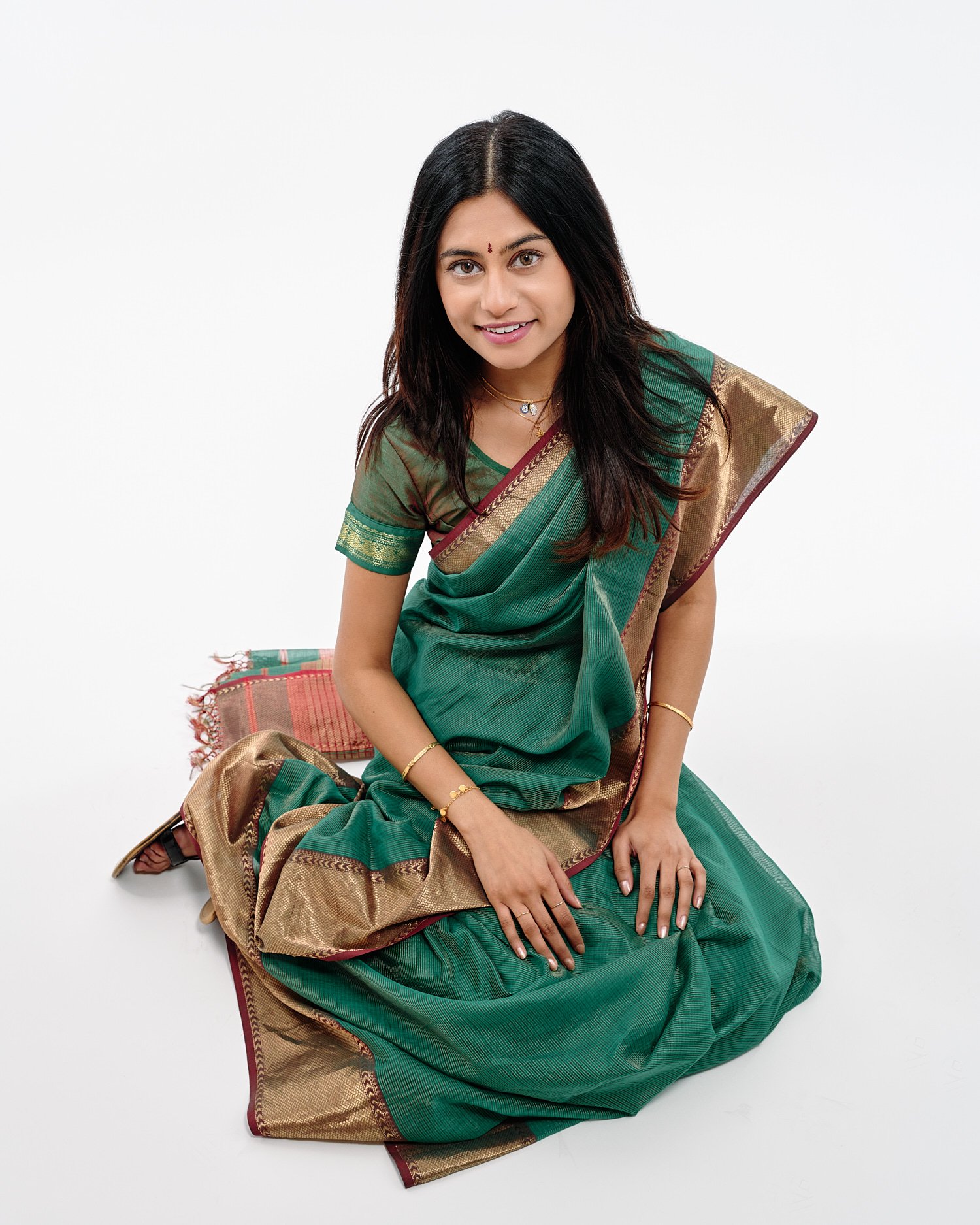  Mohandas Parappath and his wife Kanthi Menon are posing for family portraits with their daughters Kamya and Maya in a photography studio. Their bright colorful dresses pop out against white background 