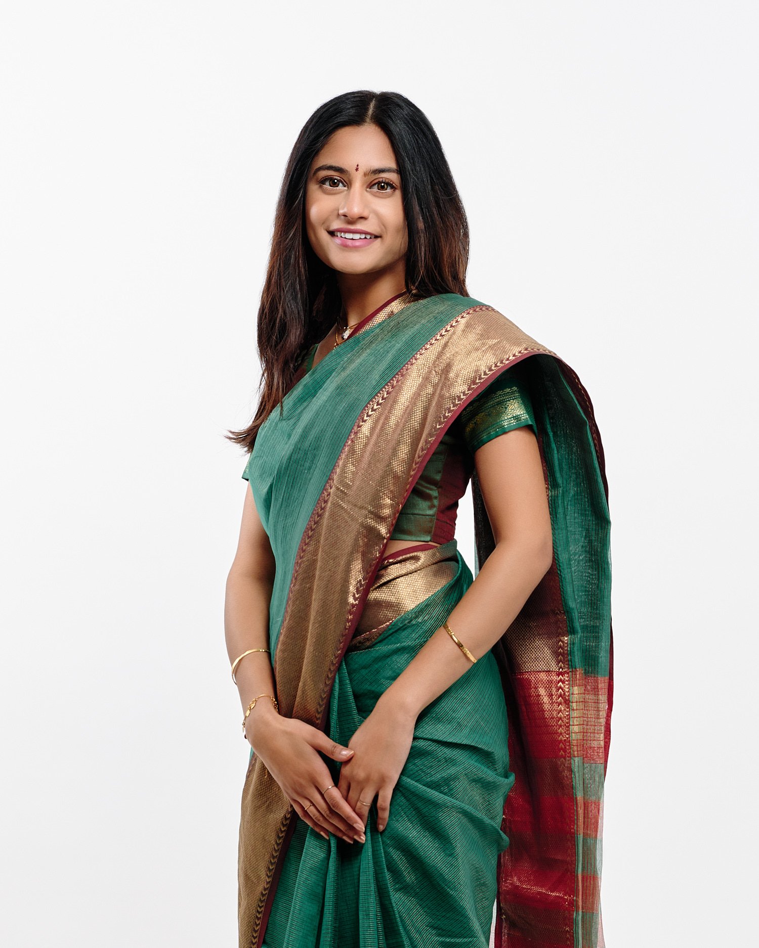  Mohandas Parappath and his wife Kanthi Menon are posing for family portraits with their daughters Kamya and Maya in a photography studio. Their bright colorful dresses pop out against white background 