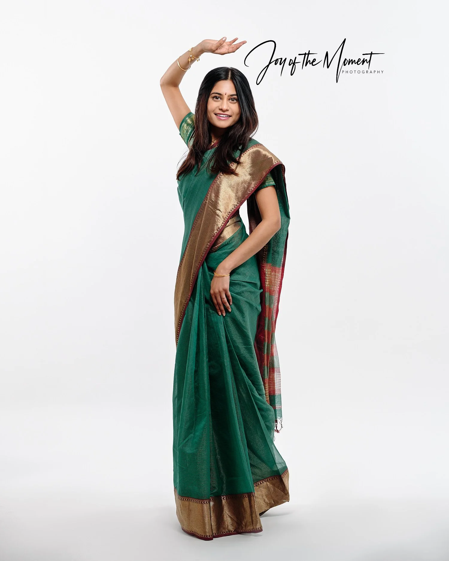  Mohandas Parappath and his wife Kanthi Menon are posing for family portraits with their daughters Kamya and Maya in a photography studio. Their bright colorful dresses pop out against white background 
