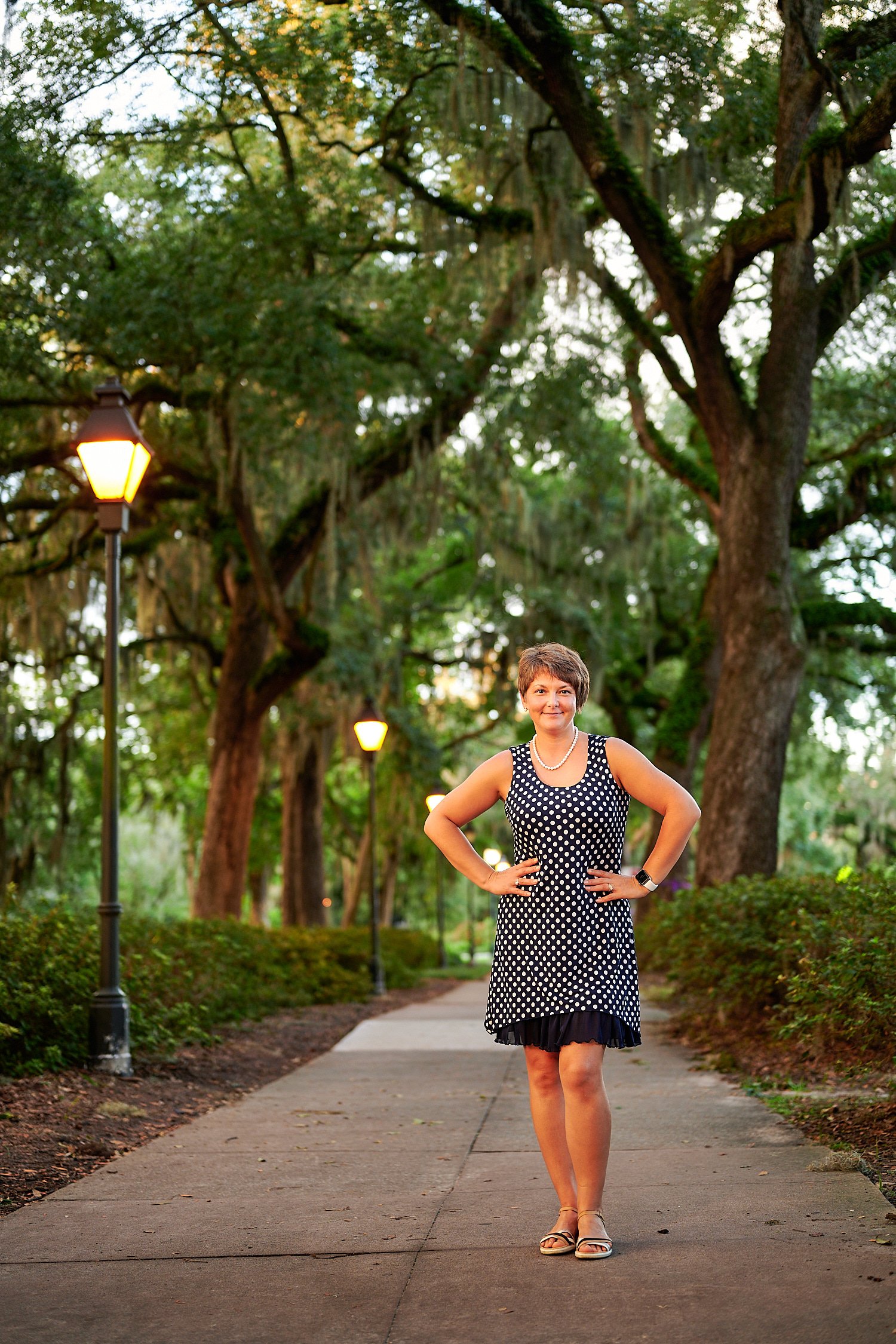  Savannah, Georgia, USA - OCTOBER 9TH 2021: a 44-year-old woman is posing in the streets of Savannah on a warm autumn evening lit by the setting sun. She had short hair and a top with circle ornaments. 