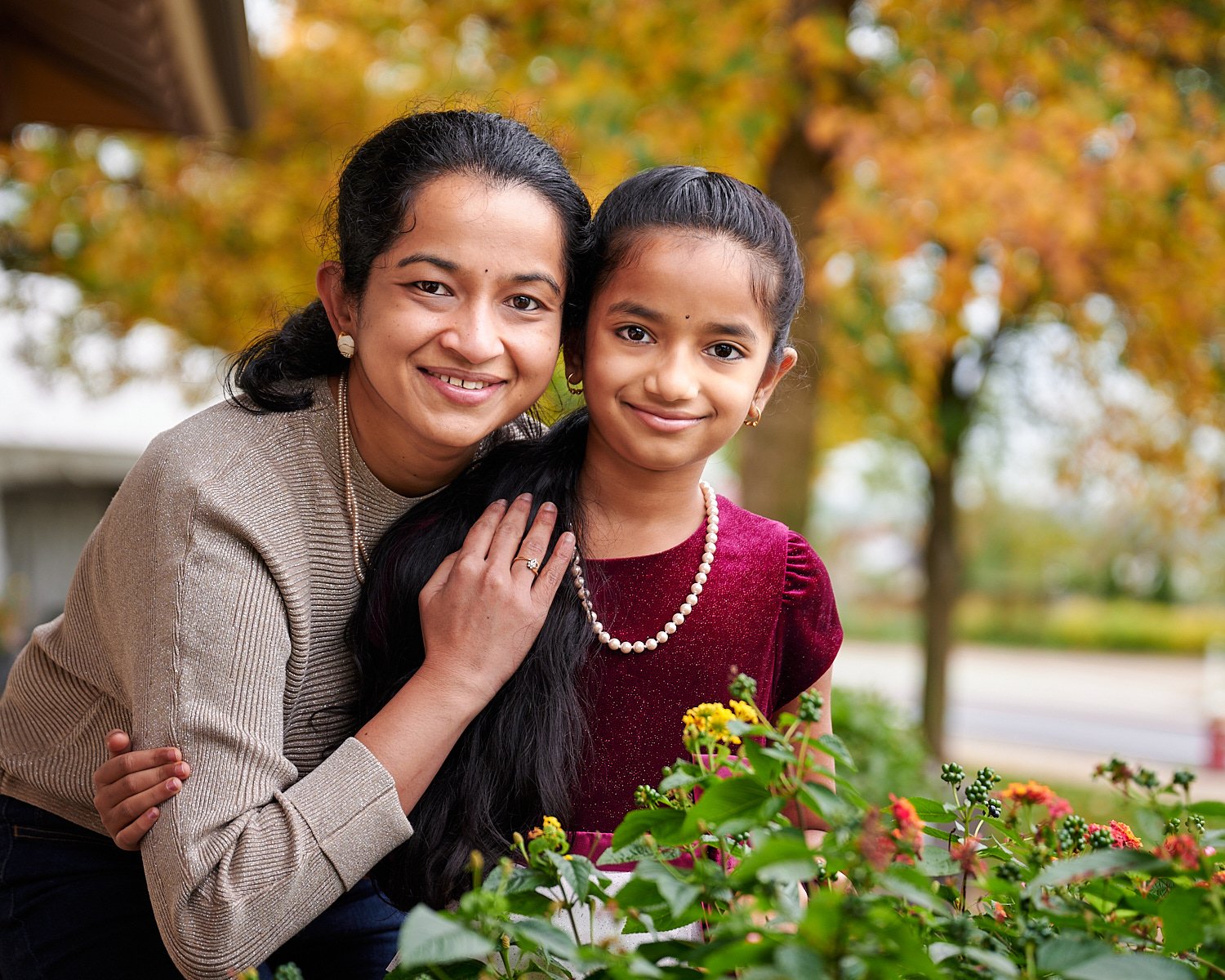  Mother is posing with her pre-teen daughter in front of Phipps Conservatory and Botanical Gardens of Pittsburgh, Pennsylvania. The girl is wearing a burgundy ball dress and pearls. 