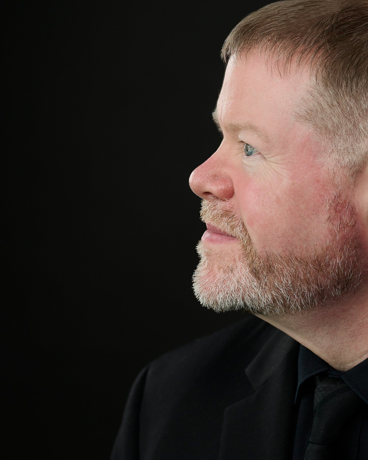  Tim Heavner is posing for his business headshots in a professional photography studio with a dark black background. Timothy is a pianist and is portrayed with his keyboard full length and close-up. 