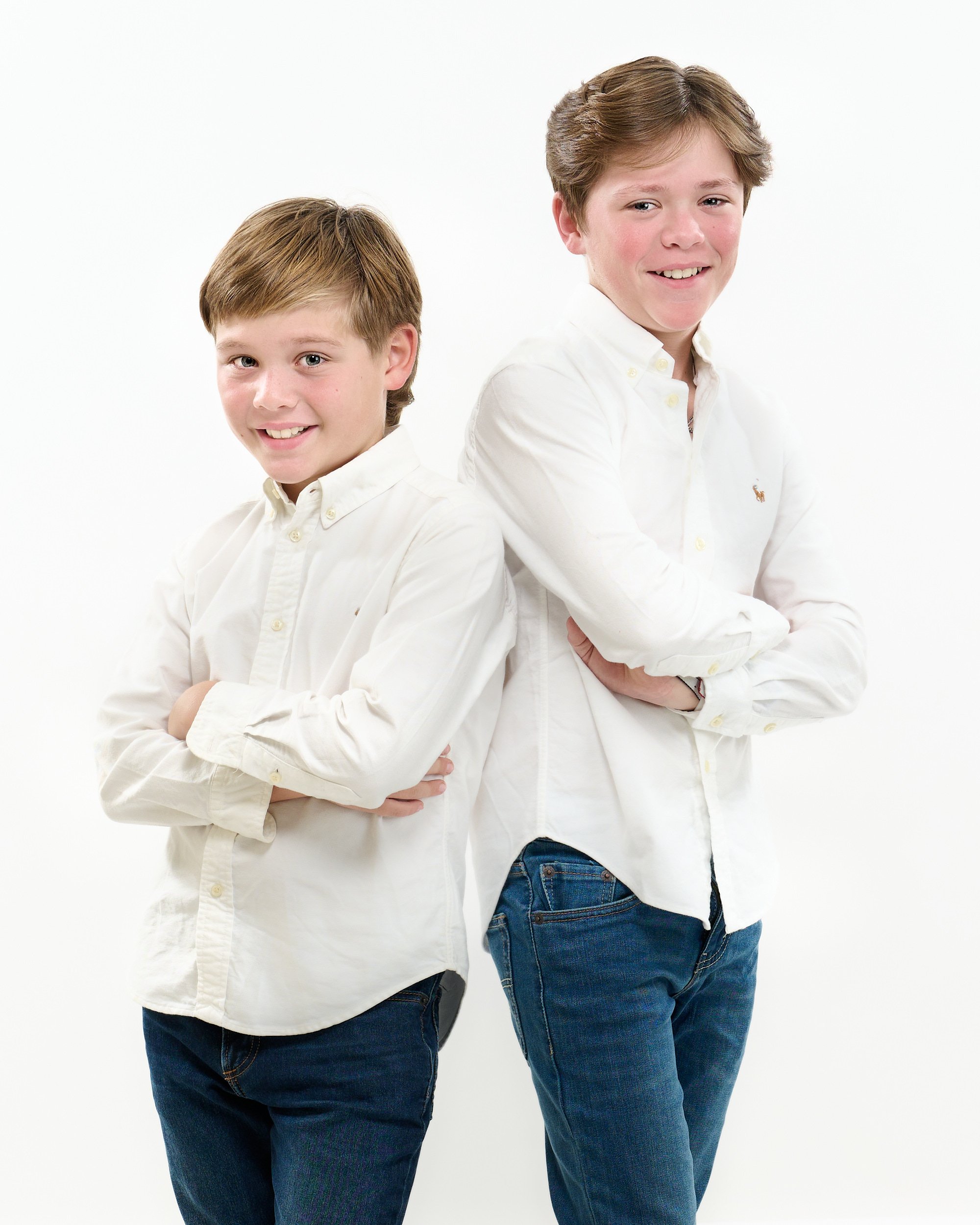  THE WOODLANDS, TEXAS - DECEMBER 2022: Emily Braud is posing for high key mono-color portraits with her husband and two sons. They wear white shirts and blue jeans and look happy and healthy. 