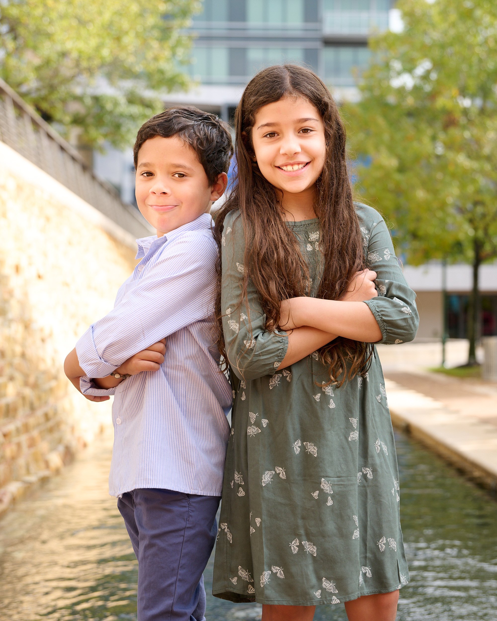  THE WOODLANDS, TEXAS - DECEMBER 2022: photo session in the Woodlands Waterway Square. Jayme Meyer’s two children are posing for family portraits. The young brother and sister are smiling playfully. 