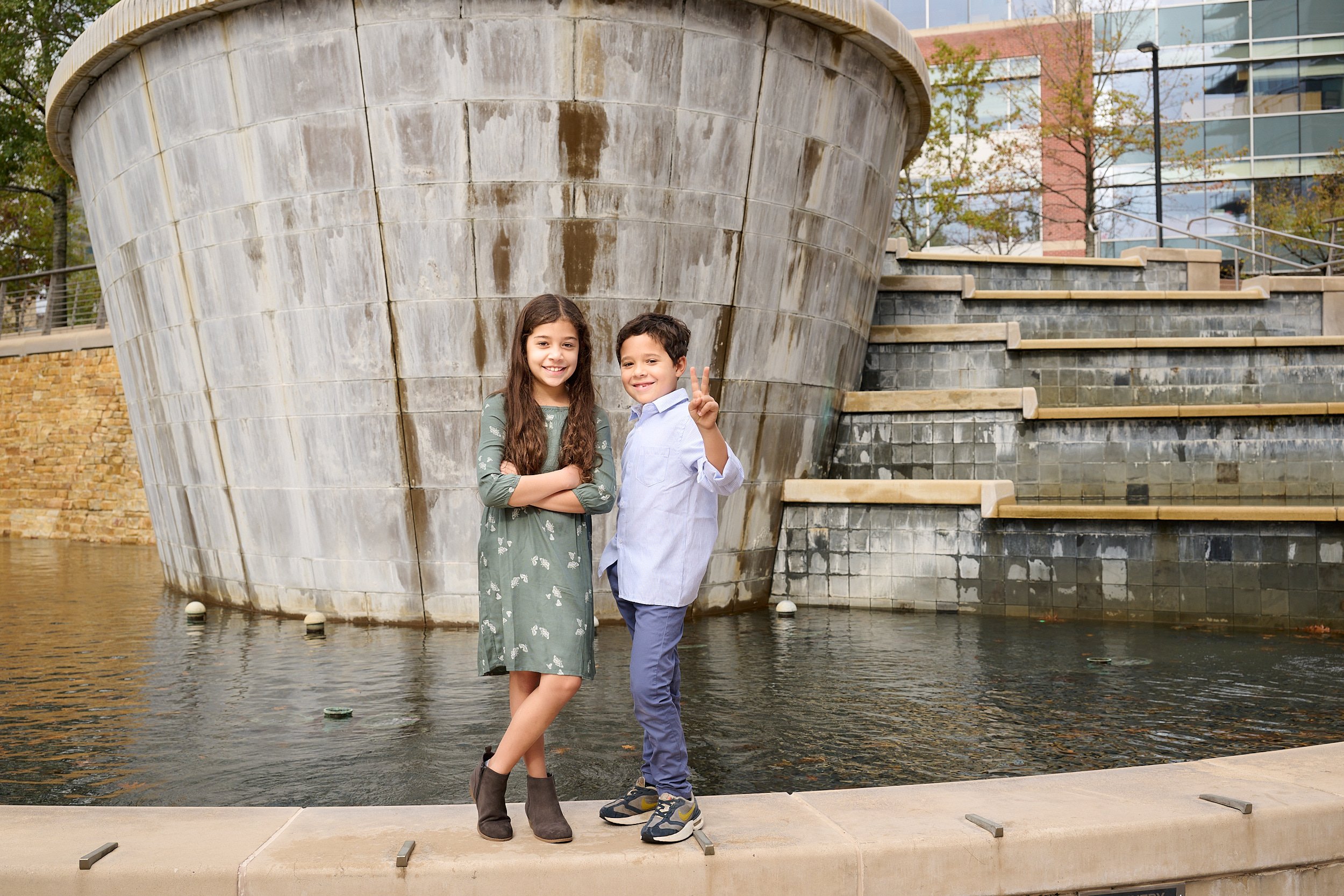  THE WOODLANDS, TEXAS - DECEMBER 2022: photo session in the Woodlands Waterway Square. Jayme Meyer’s two children are posing for family portraits. The young brother and sister are smiling playfully. 