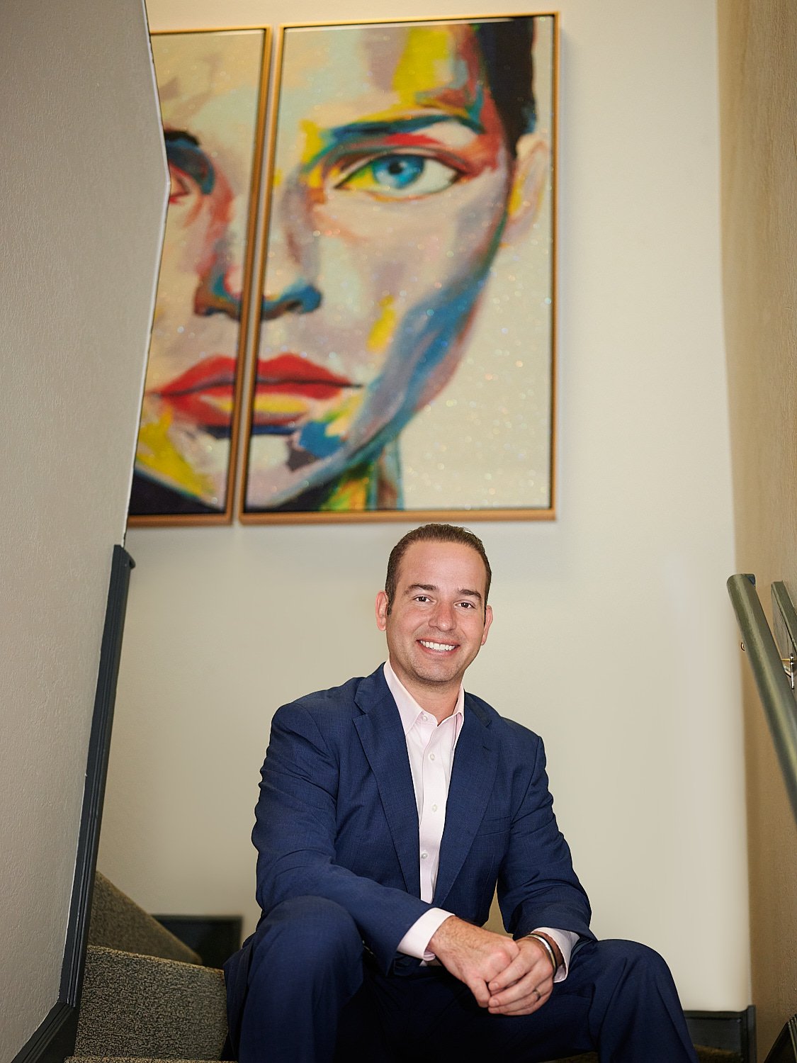  THE WOODLANDS, TEXAS - MARCH 2023: plastic surgeon is posing for environmental business headshots in his medical clinic full of beautiful artwork. He is dressed in a business suit without a tie 
