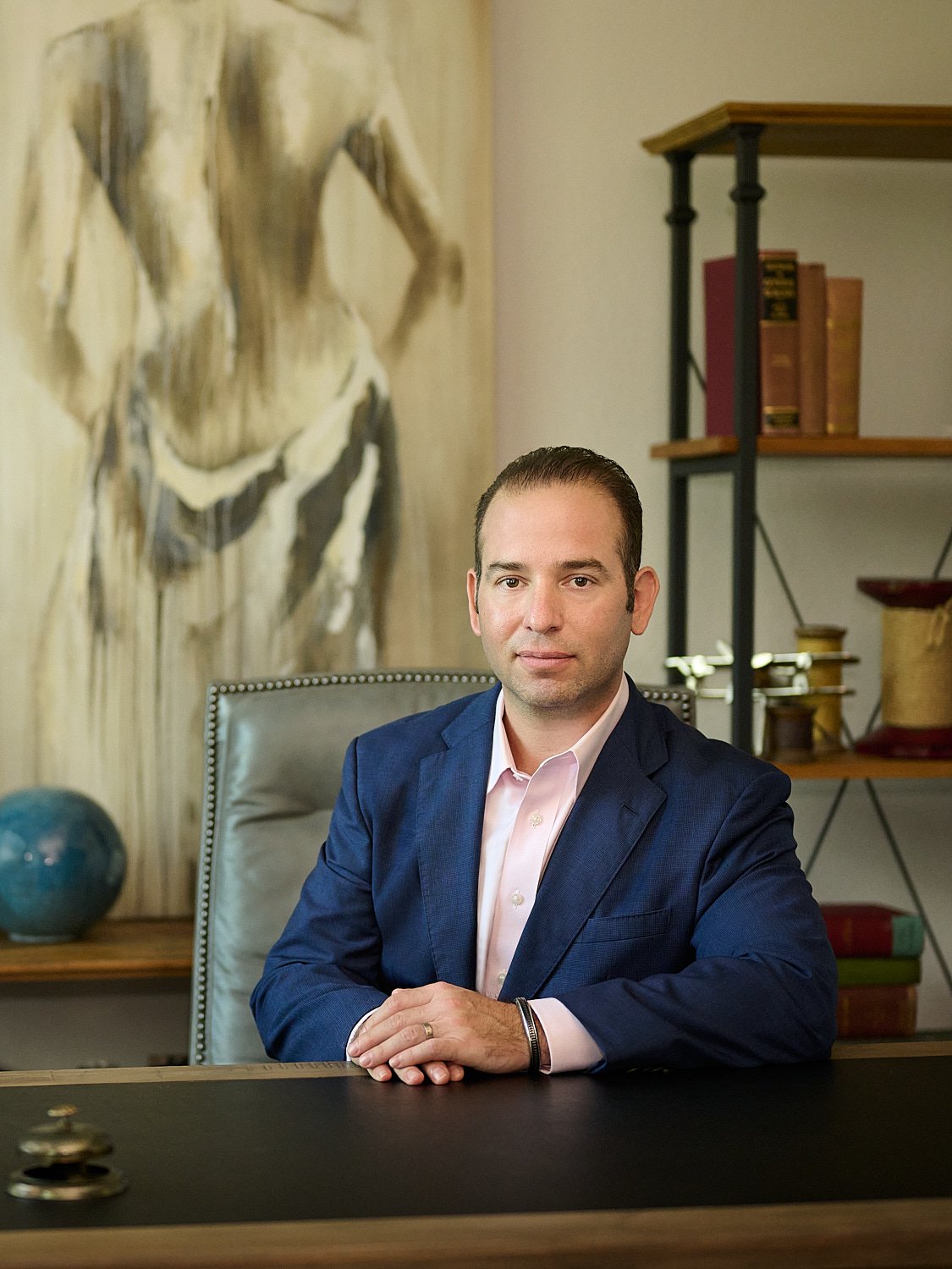  THE WOODLANDS, TEXAS - MARCH 2023: plastic surgeon is posing for environmental business headshots in his medical clinic full of beautiful artwork. He is dressed in a business suit without a tie 