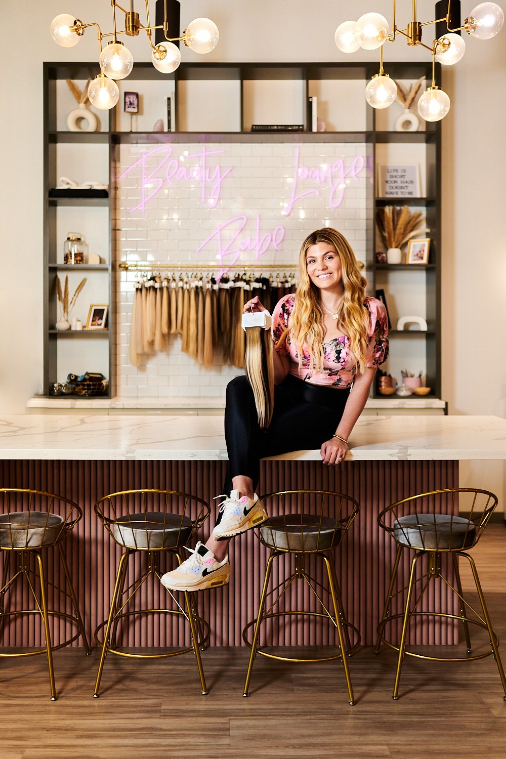  THE WOODLANDS, TEXAS - MAY 5TH 2023:  a female manager of The Beauty Lounge salon is posing for a business portrait in the salon against her company logo. She holds a professional hair extension set 