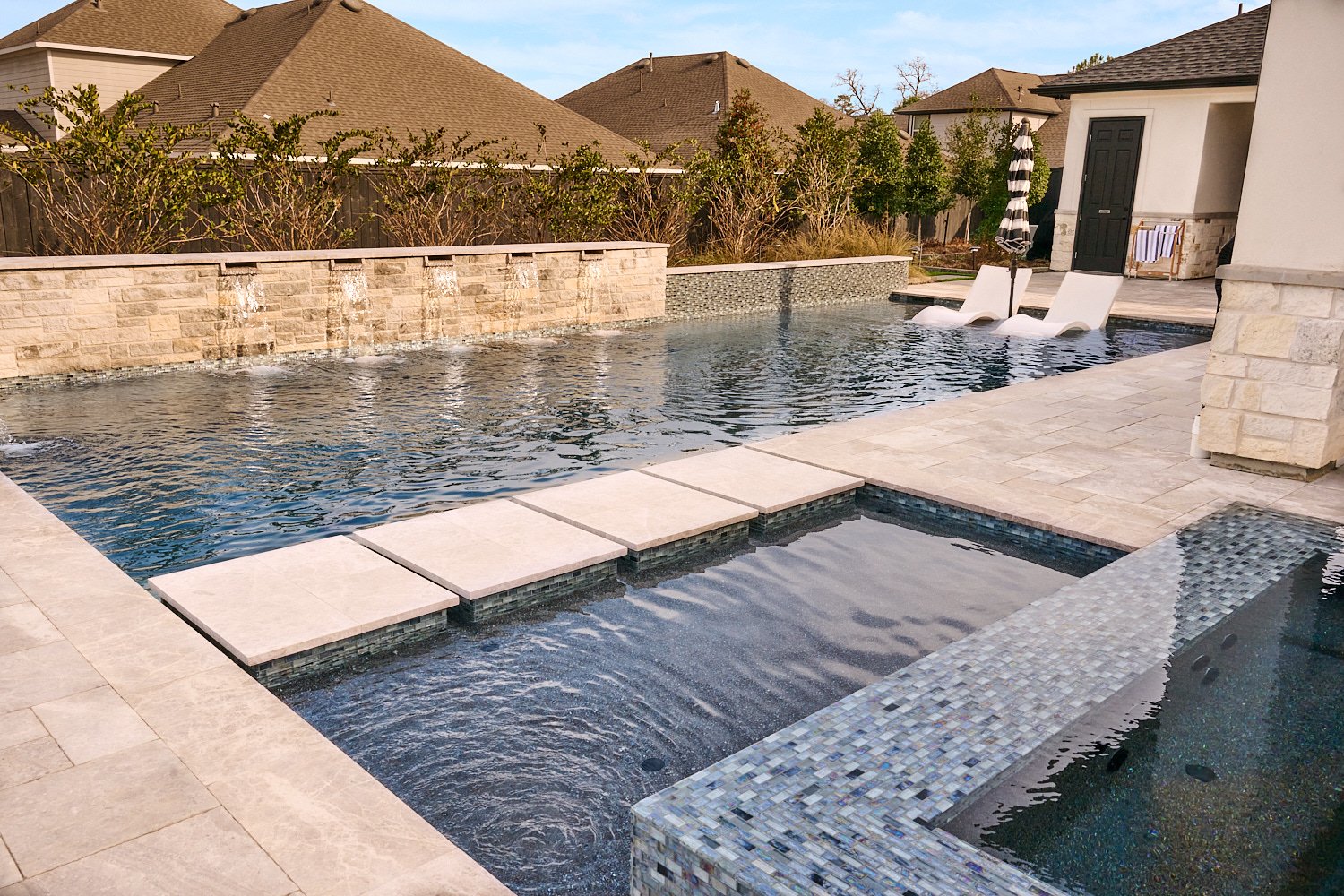  CONROE, TEXAS - JANUARY 2023: wide shots and close ups of a fully equipped outdoor kitchen, a covered patio, a swimming pool with scuppers, a spa with perimeter overflow and a fire pit with chairs. 