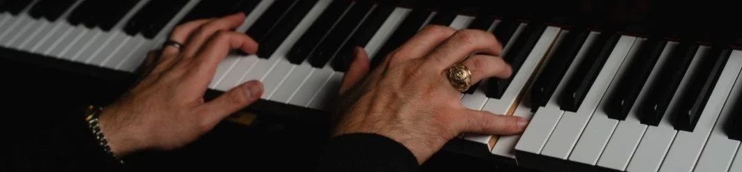 Two hands on a Yamaha upright piano.