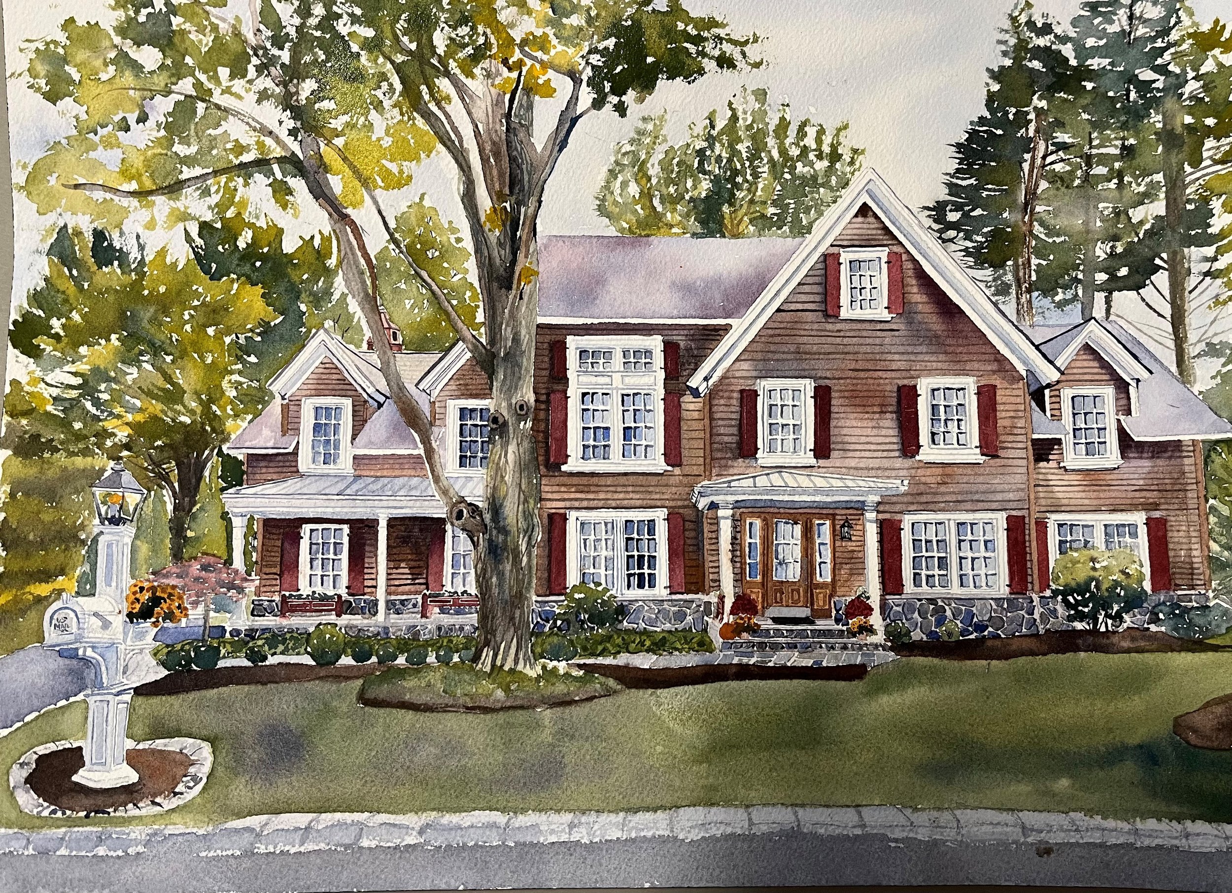 A watercolor painting of a large, two-story wooden house surrounded by trees and landscaped garden. The house has a stone foundation, multiple windows with red shutters, and a central front door with steps. There is a white lamp post and a small foun