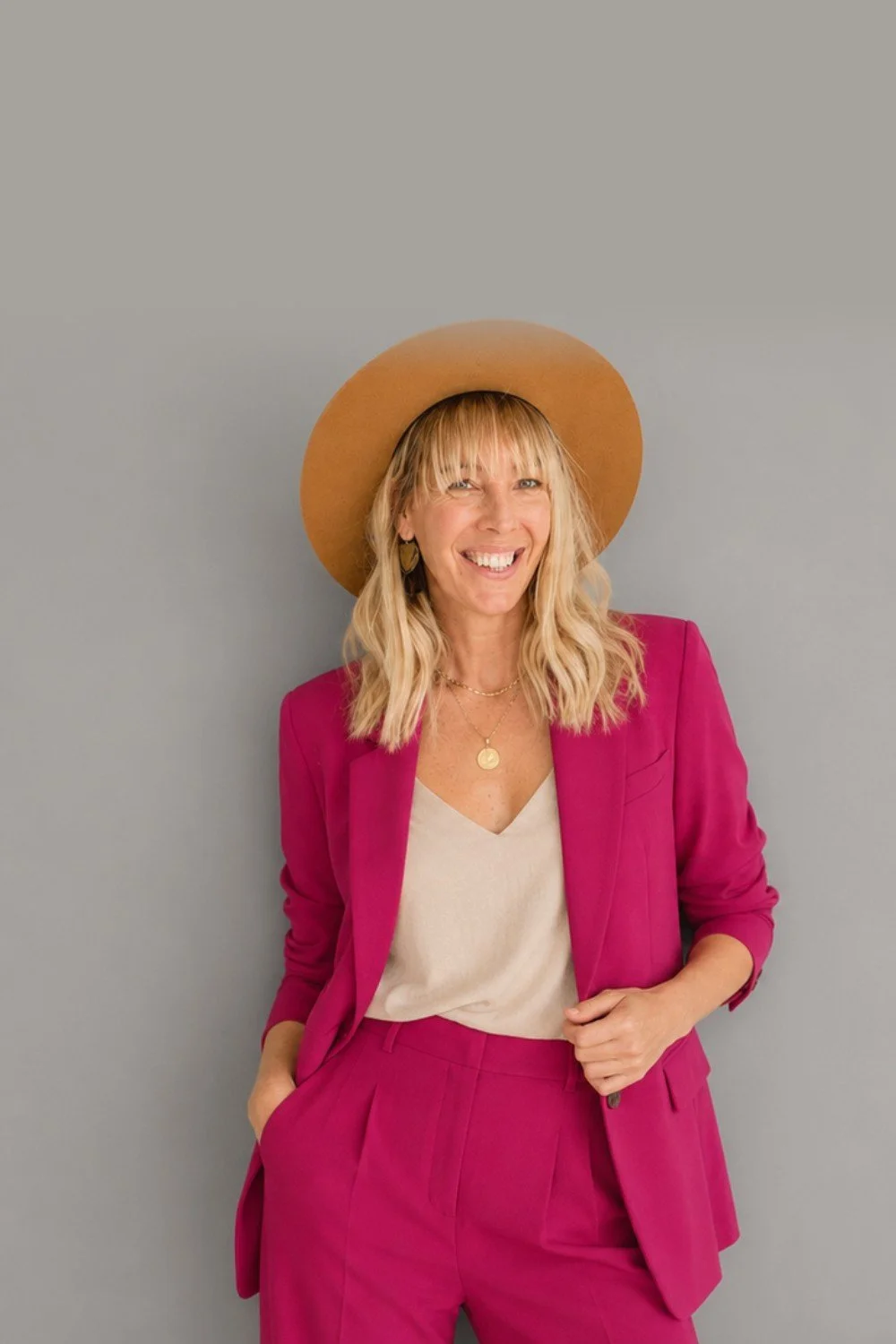 Kristen Kellogg smiling in a pink suit and hat