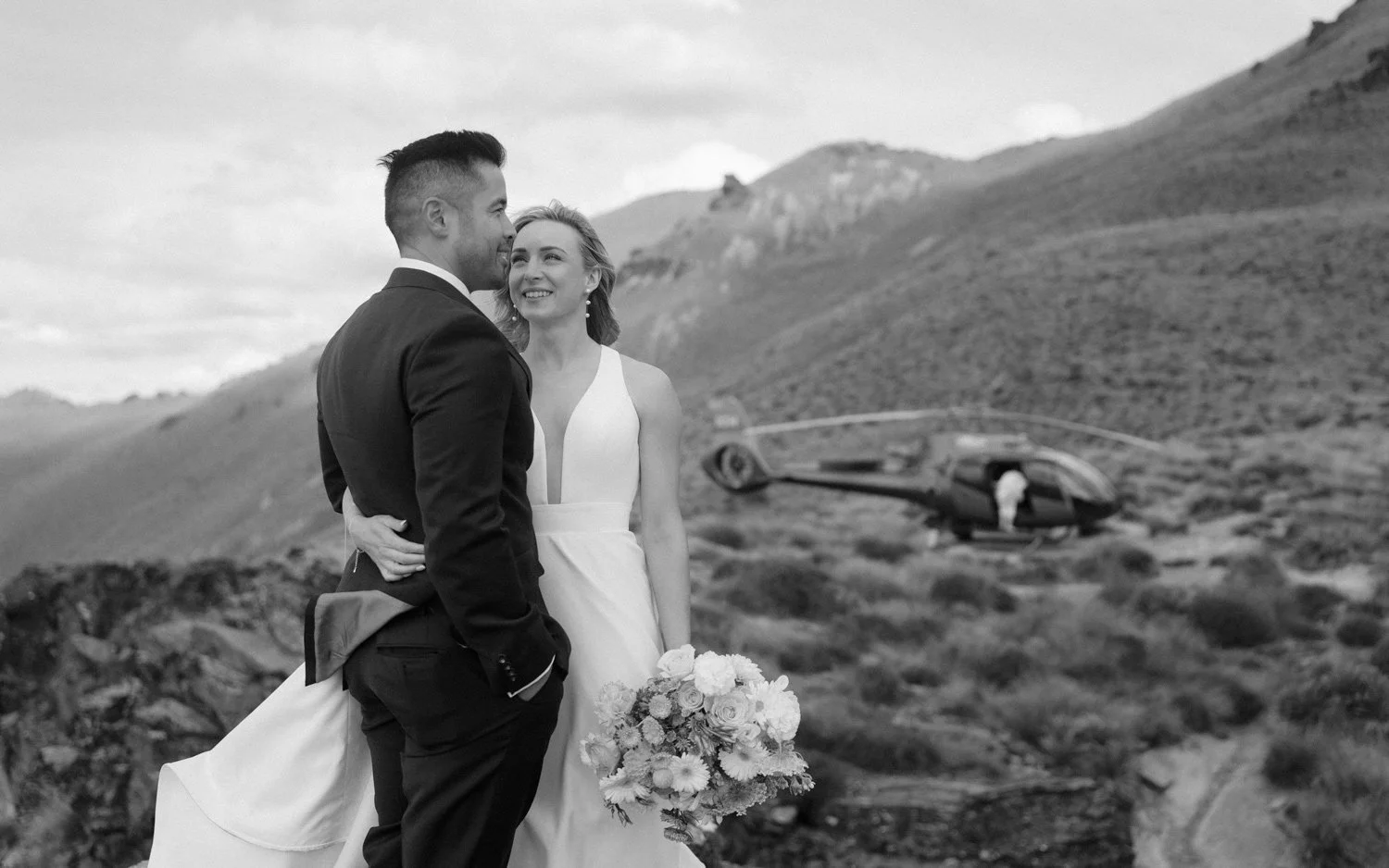 Queenston heli elopement couple posing by helicopter at Cecil Peak, The remarkables in the background