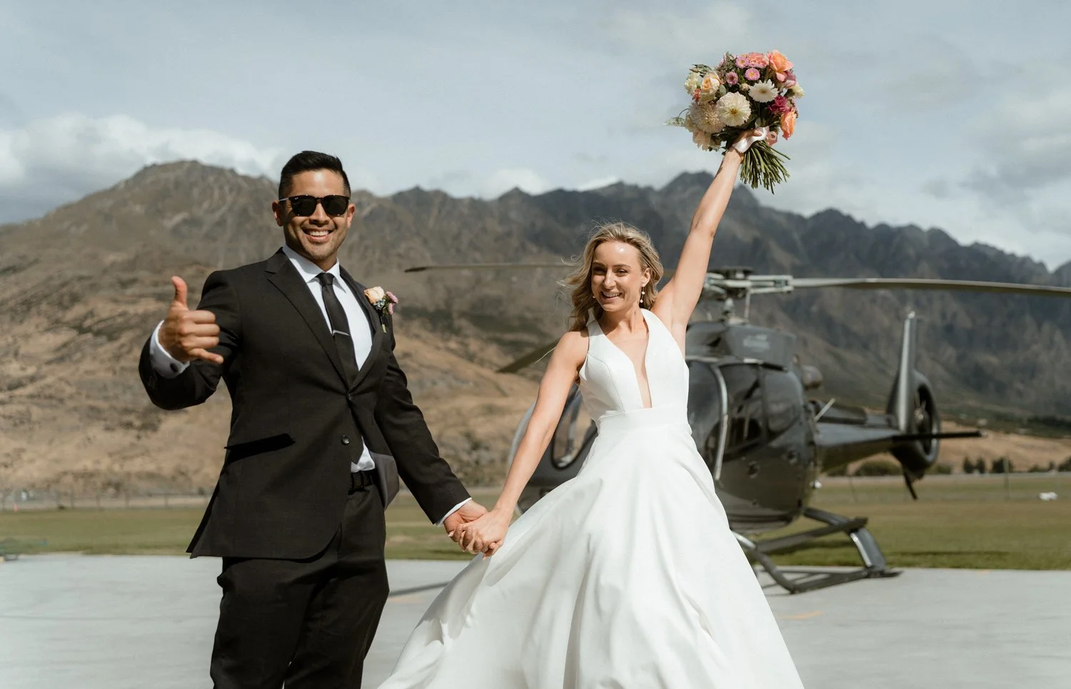 bride celebrating with wedding flowers in front of heli in Queenstown