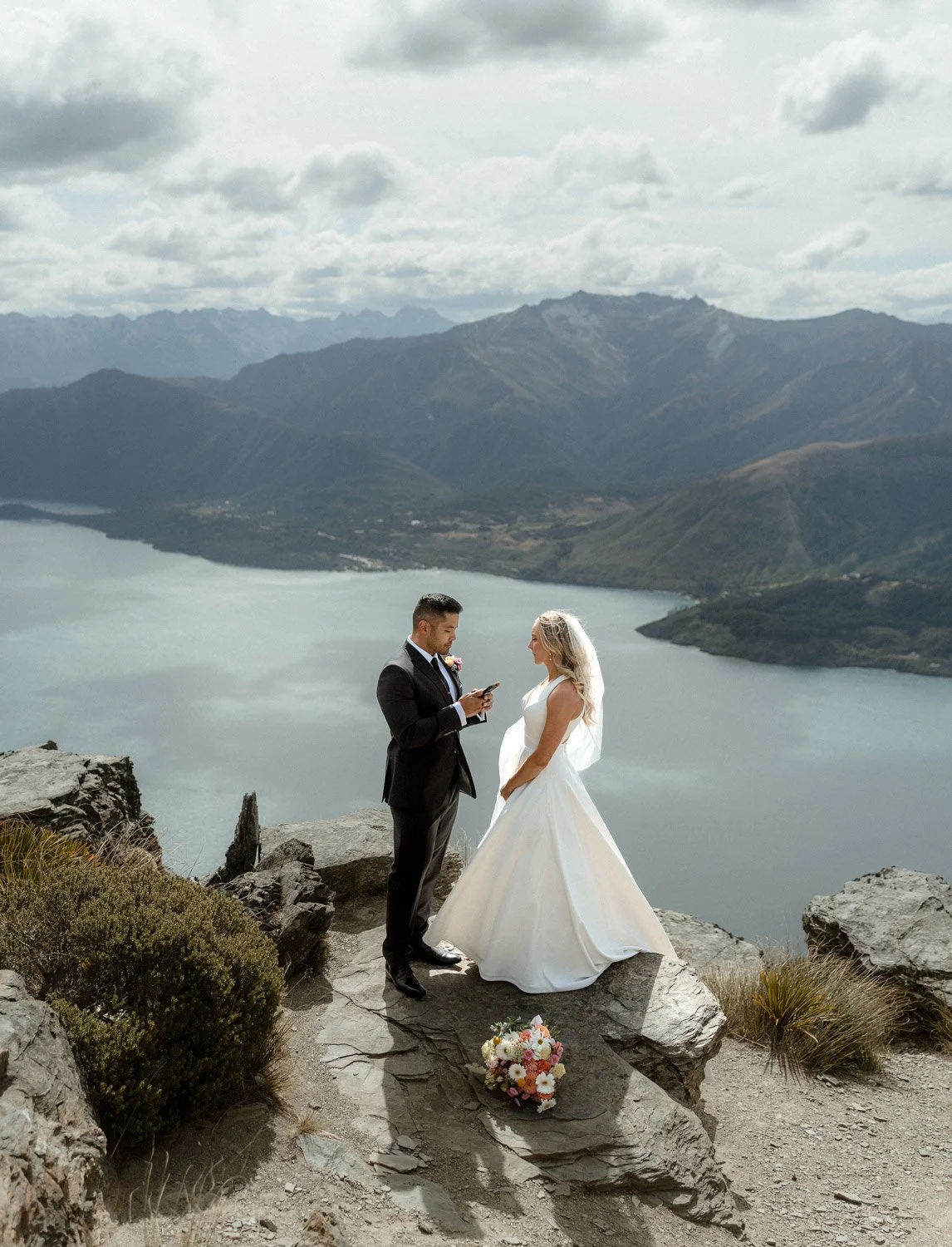 groom reading vows on Cecil Peak with Summer sun and lake Wakatipu in the background