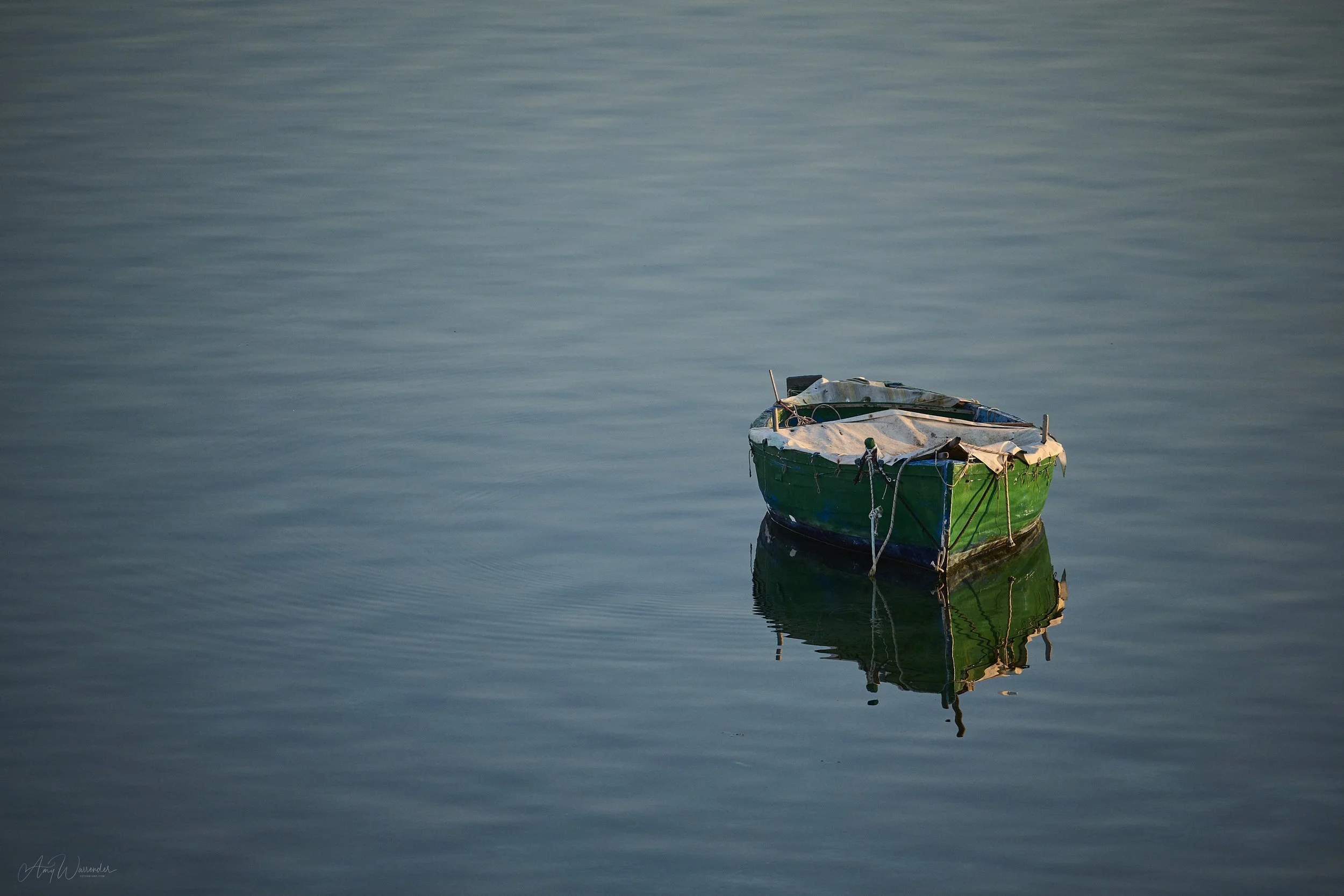 Solo row boat bobs in the evening sunset in an Italian inlet.
