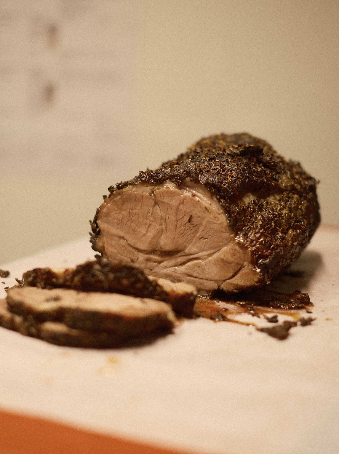 Stekt kjøttstykke med krydret skorpe, skåret opp på et hvitt underlag.