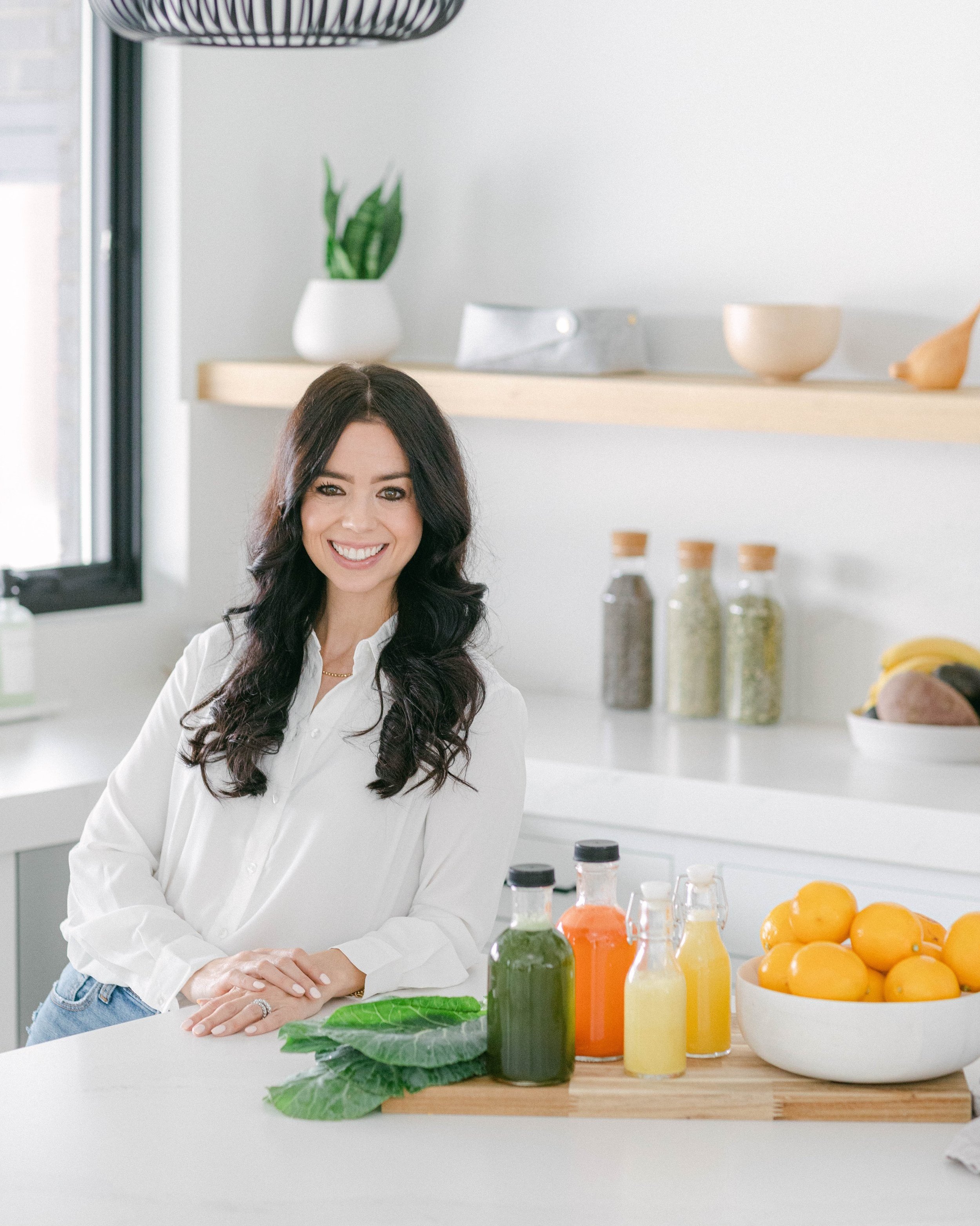 Woman sitting on a gray sofa in a modern living room with large windows and minimalist decor.