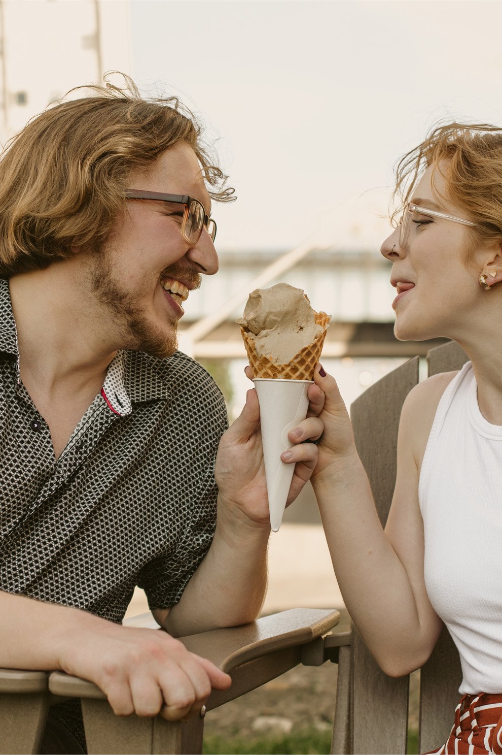 A man and woman sharing a smile while holding an ice cream cone between them
