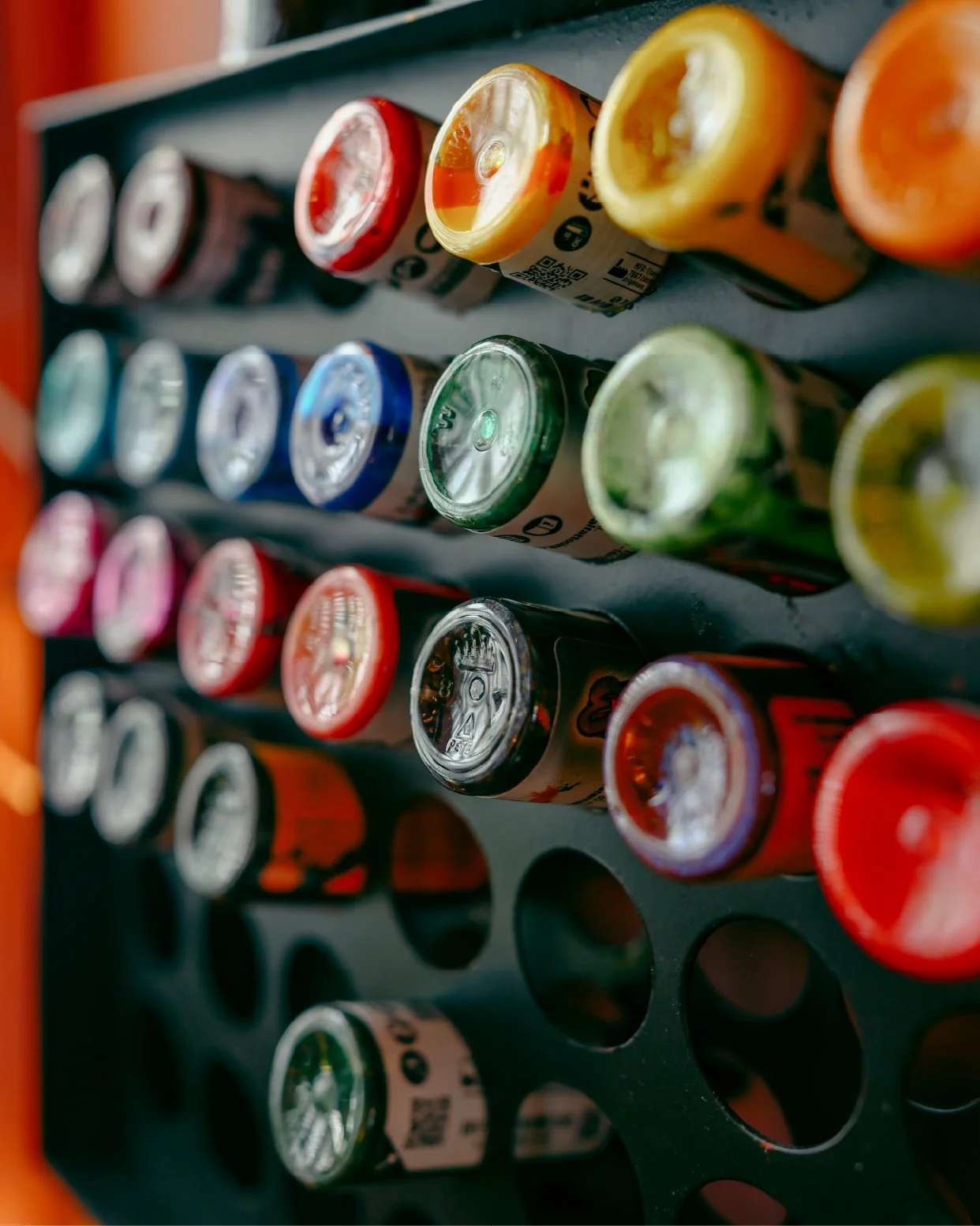 A display of colorful soda cans arranged in a black holder.