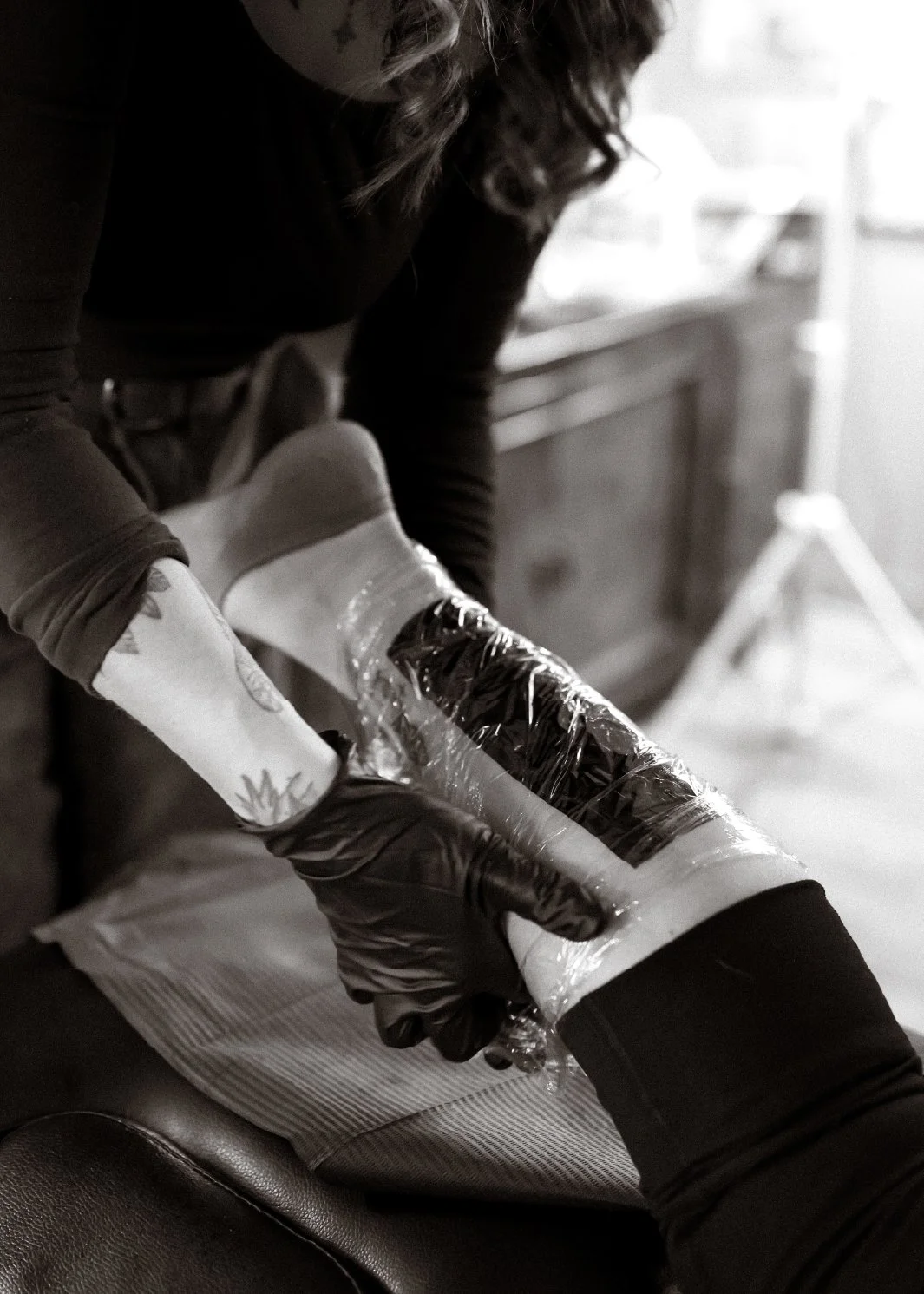 Person wearing black gloves handling a candied apple wrapped in plastic.
