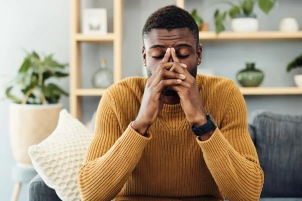 Young man with fibromyalgia pain rubbing his forehead
