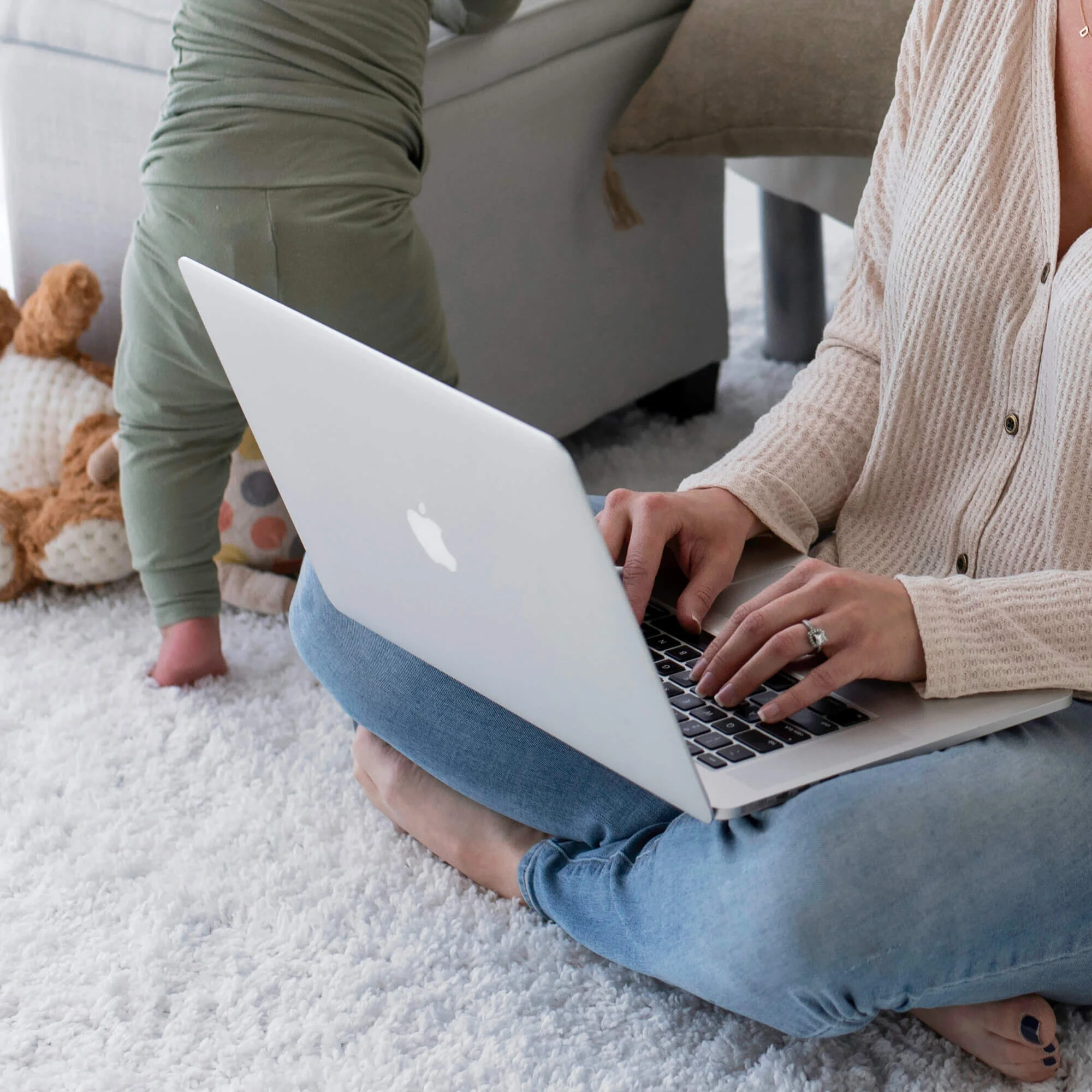 Woman entrepreneur in jeans sitting on a rug, typing on her laptop and getting business coaching